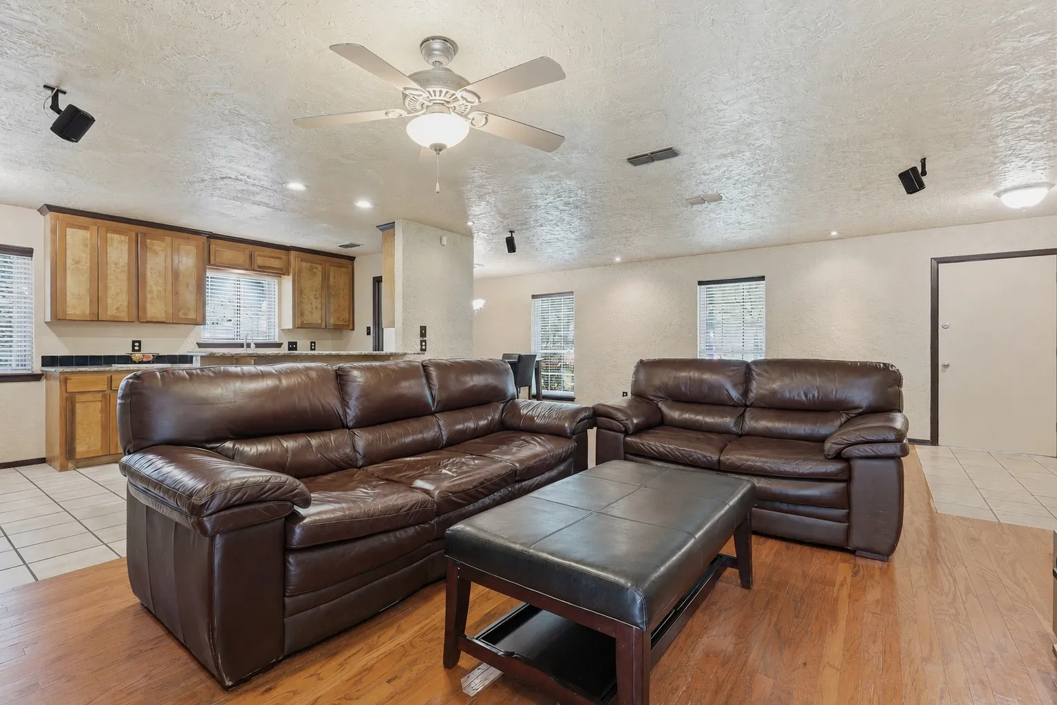 Expansive living and dining space with wood flooring, recessed lighting, fireplace, breakfast bar, and an open connection to the kitchen