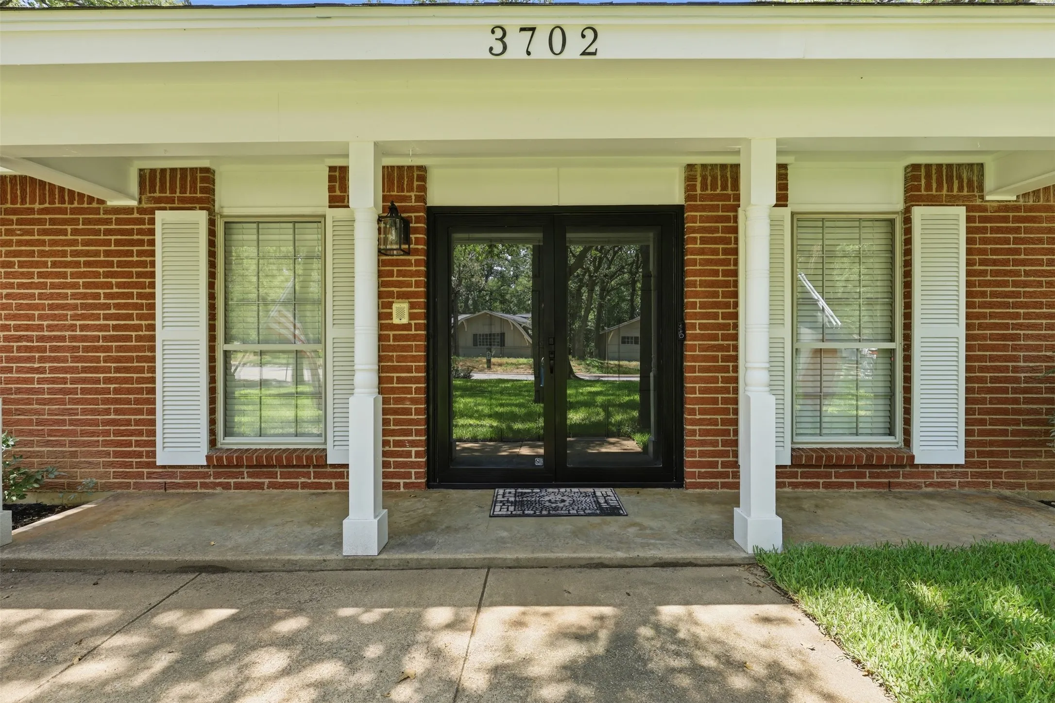 Welcoming covered front porch with entry door, classic brick exterior, and traditional architectural details
