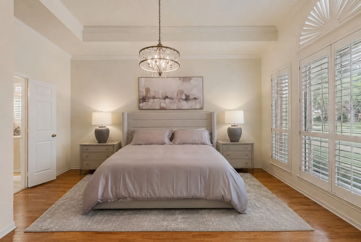Primary bedroom on the first floor with crystal chandelier and tray ceiling