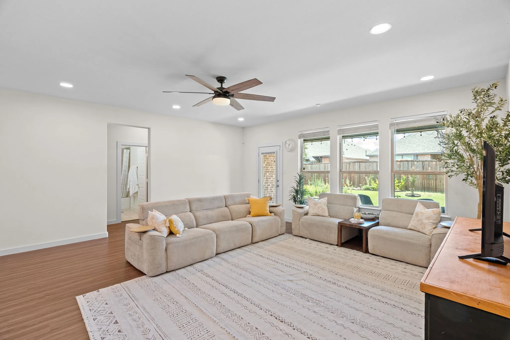 Bright living space featuring wood-finish flooring, recessed lighting, and a ceiling fan
