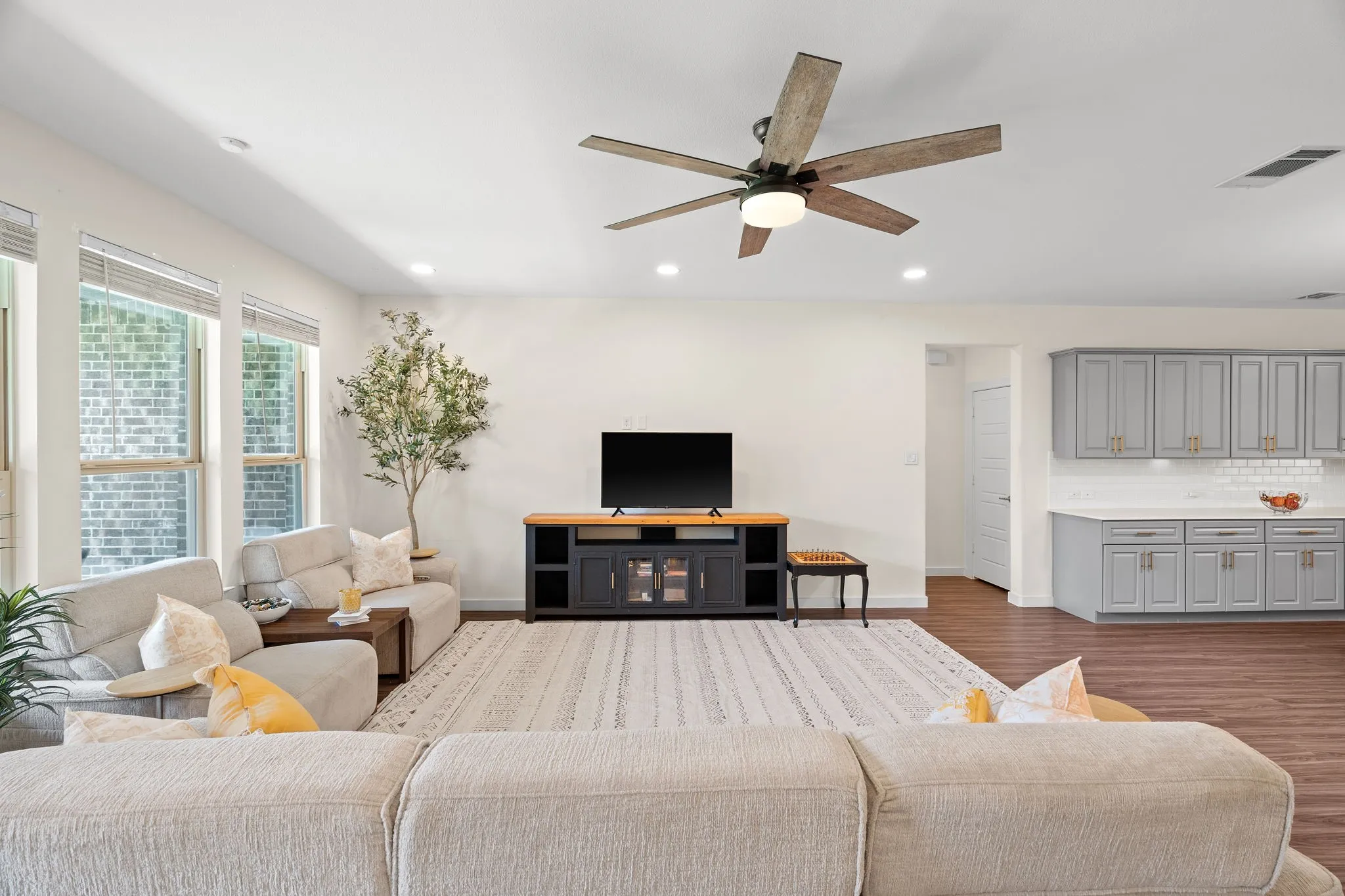 Open-concept living space featuring wood-finish flooring, a contemporary ceiling fan, recessed lighting, and large windows