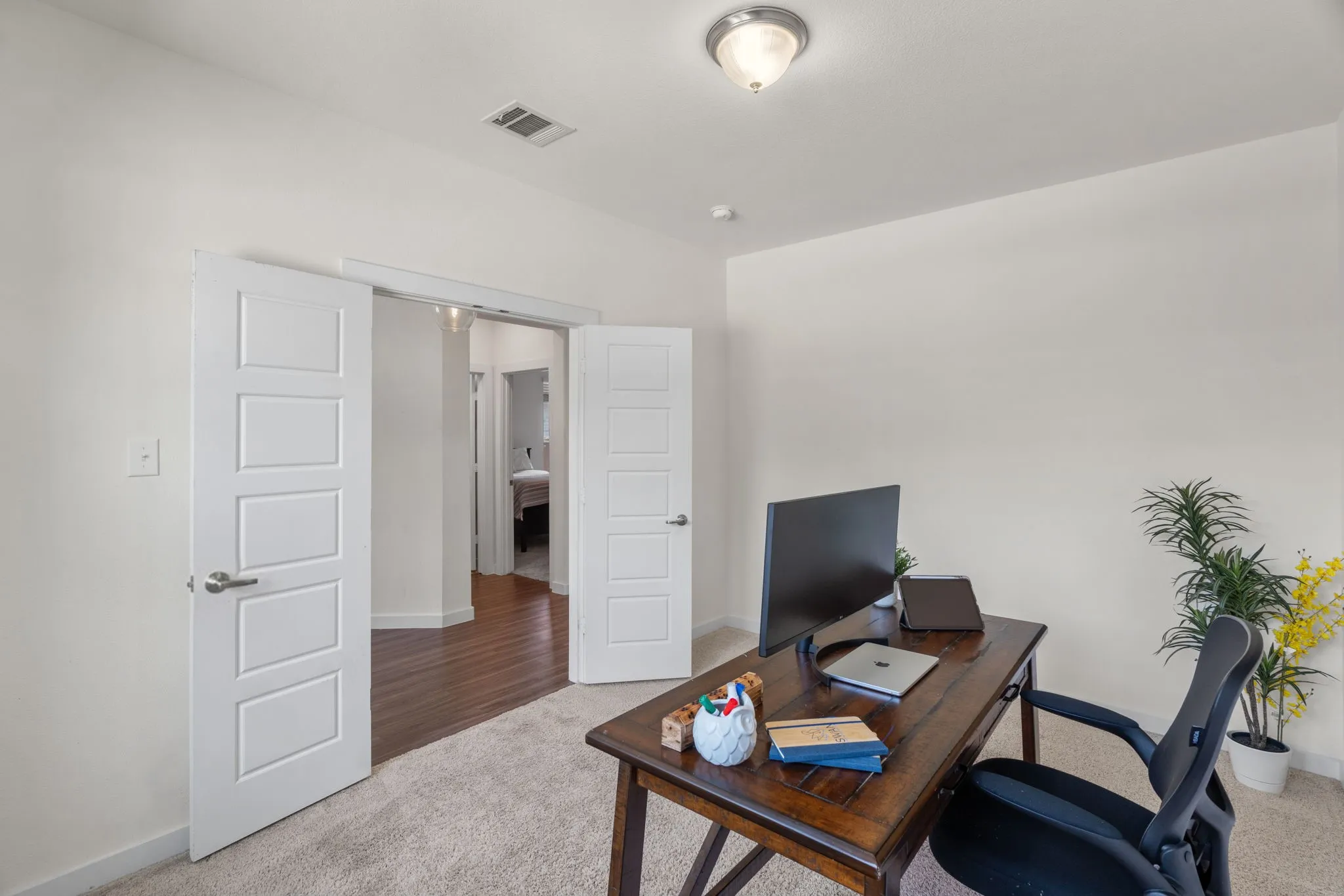 Carpeted room featuring dual paneled doors, neutral wall paint, and a flush-mount ceiling light