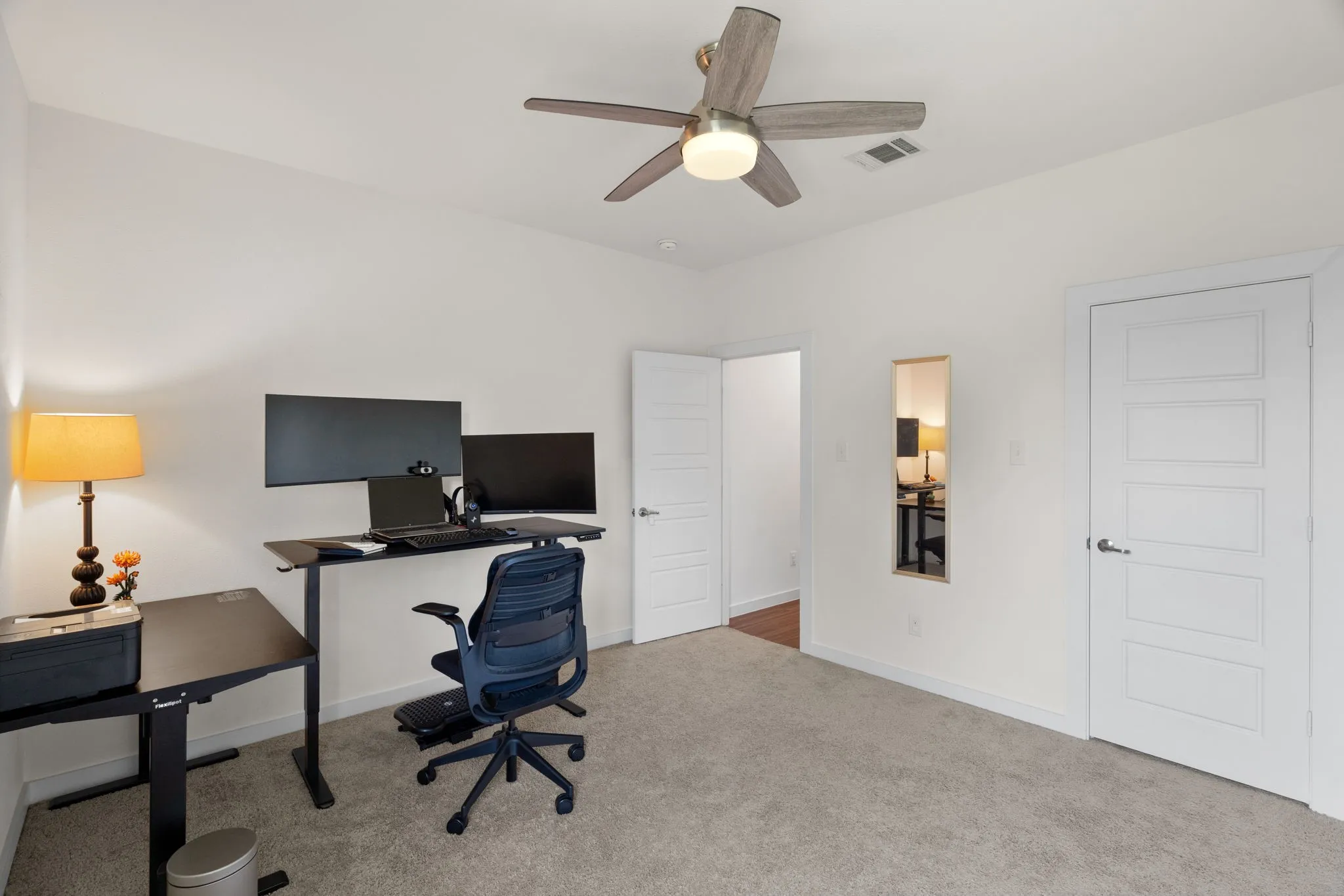 Carpeted room with a ceiling fan featuring wood-finish blades and an integrated light fixture