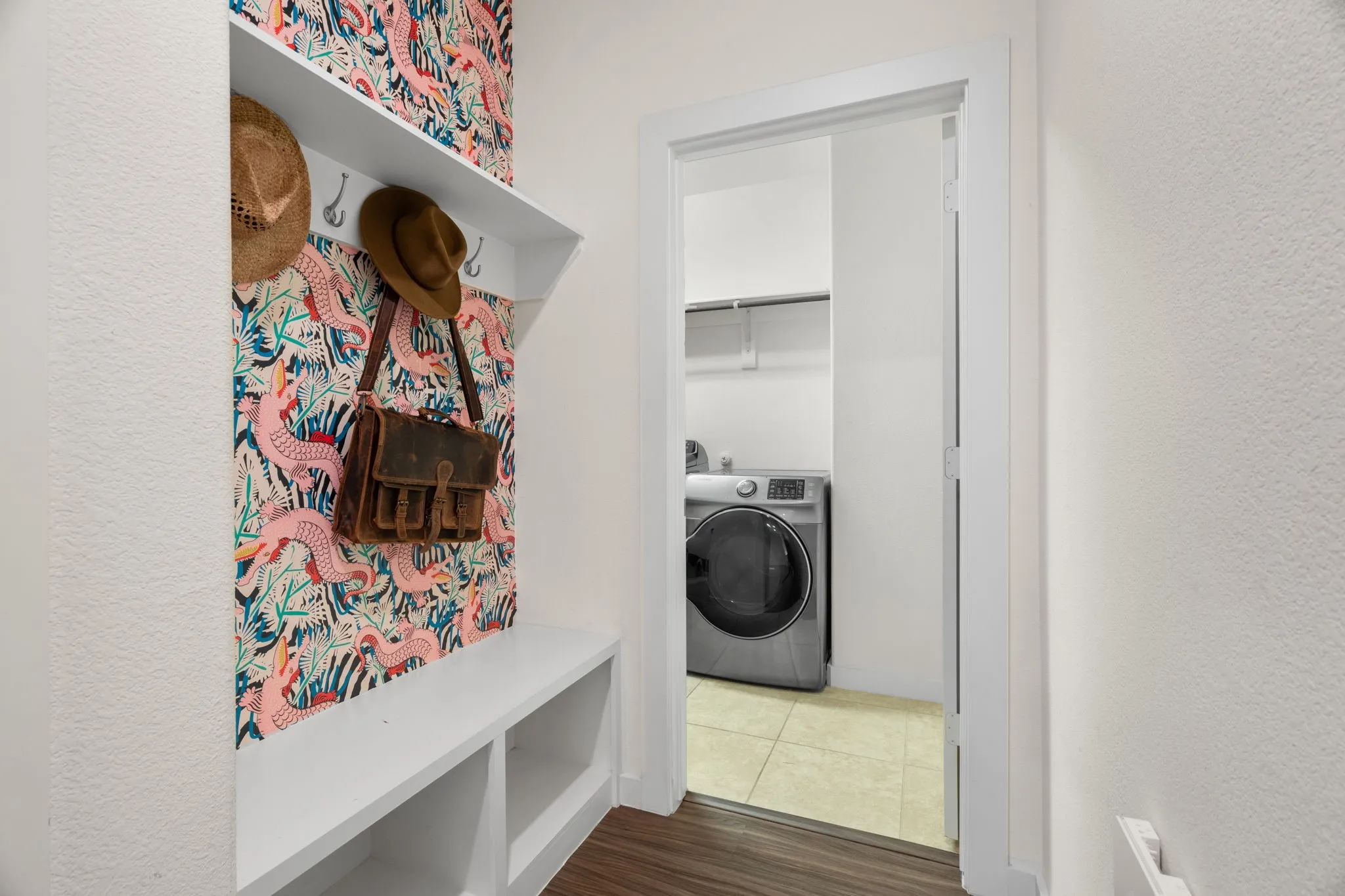 Entryway nook featuring built-in white shelving with hooks and a storage bench