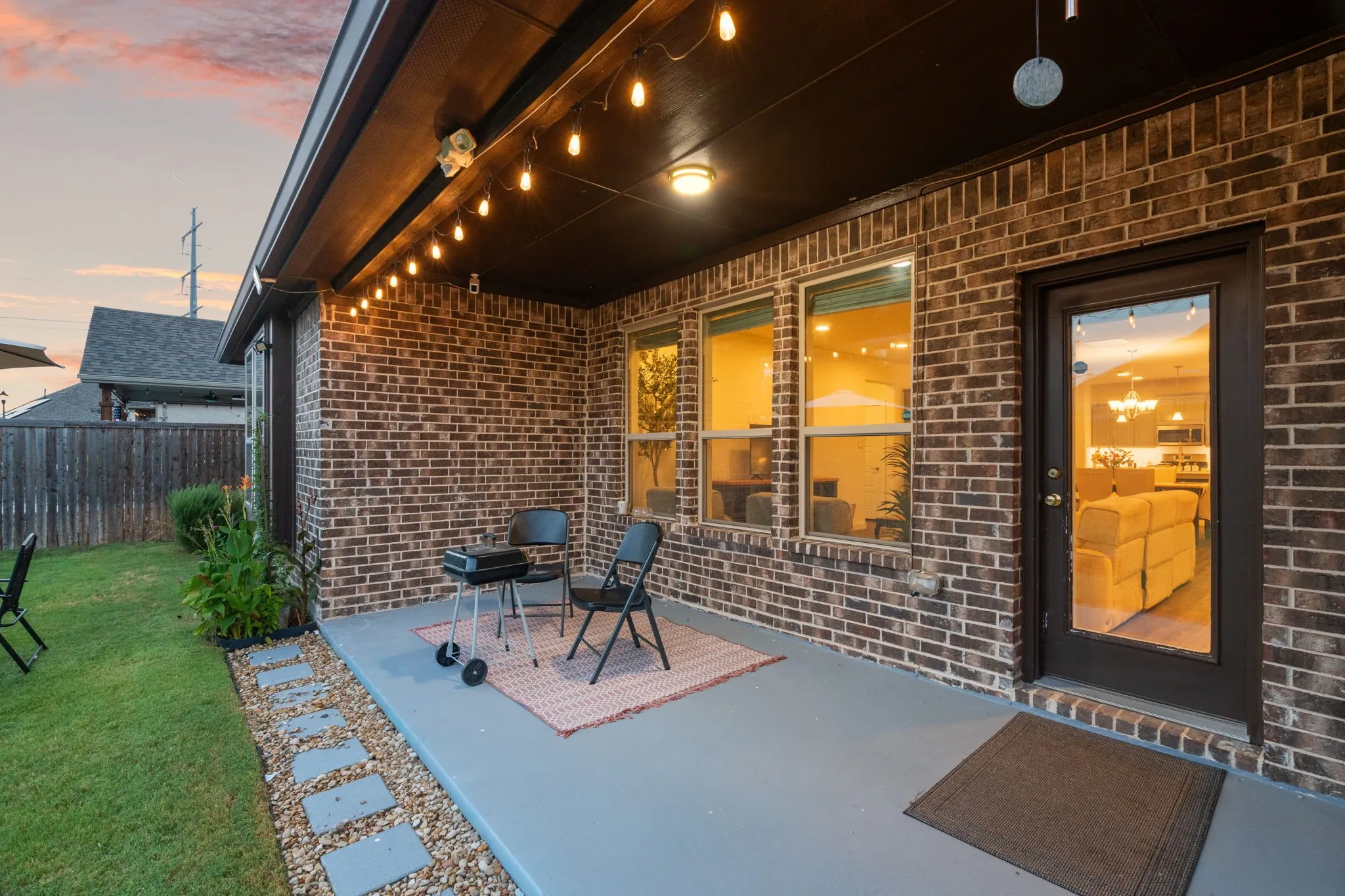 Covered patio featuring a brick exterior and string lighting