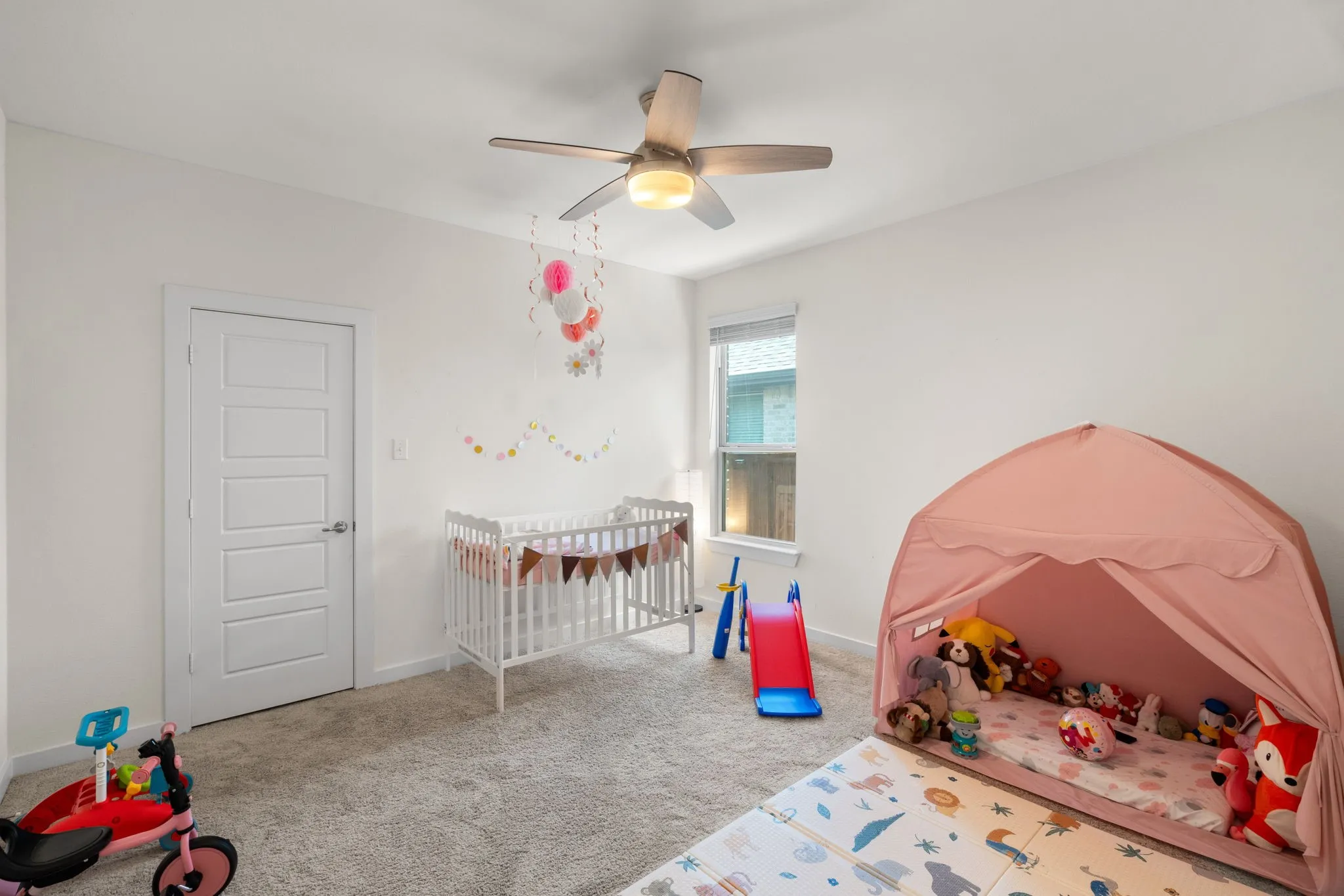 Carpeted room with a ceiling fan featuring wood-finish blades and an integrated light fixture
