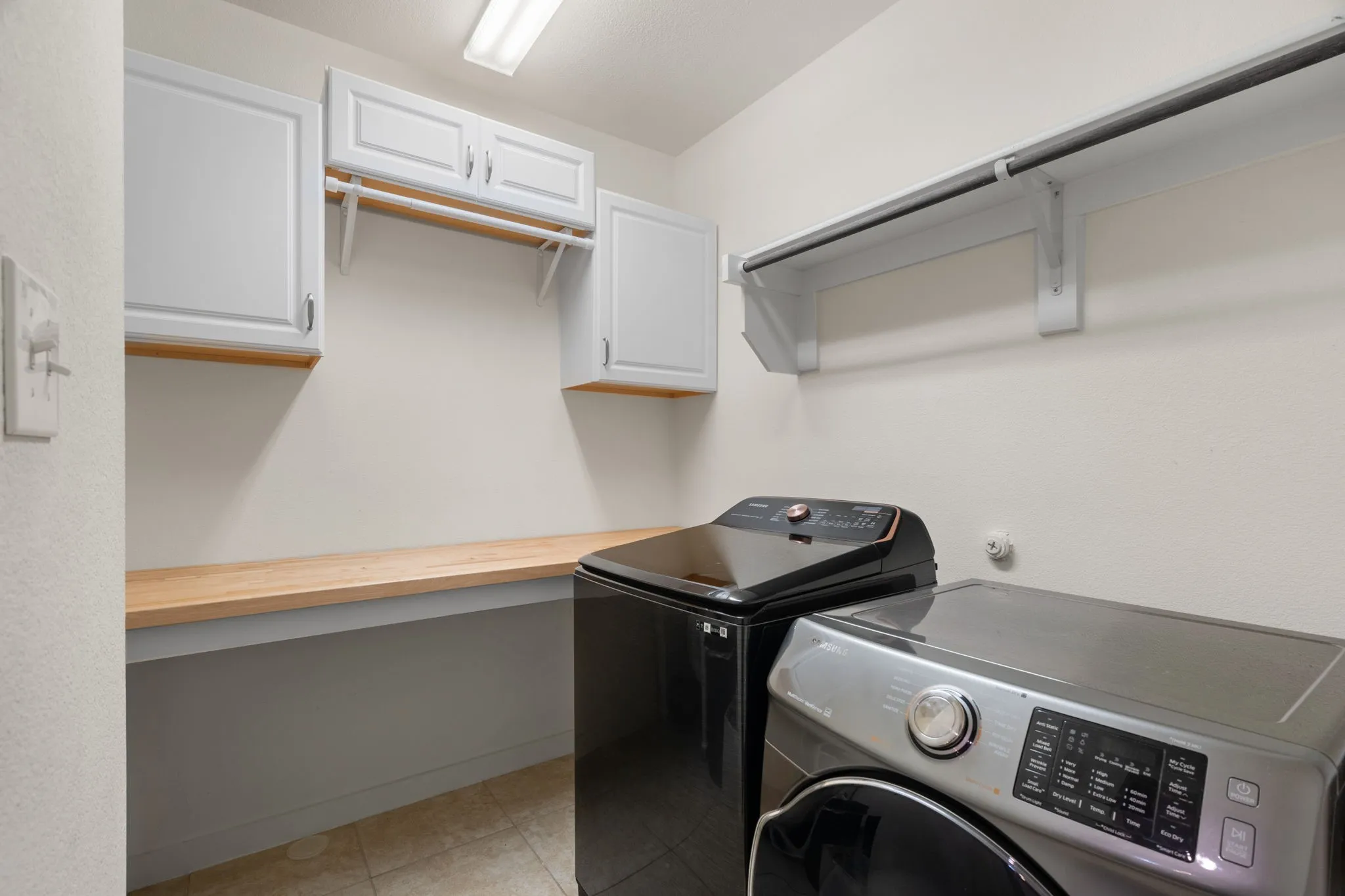 Laundry area featuring white cabinetry, a wood-finish countertop, and a clothes hanging rod