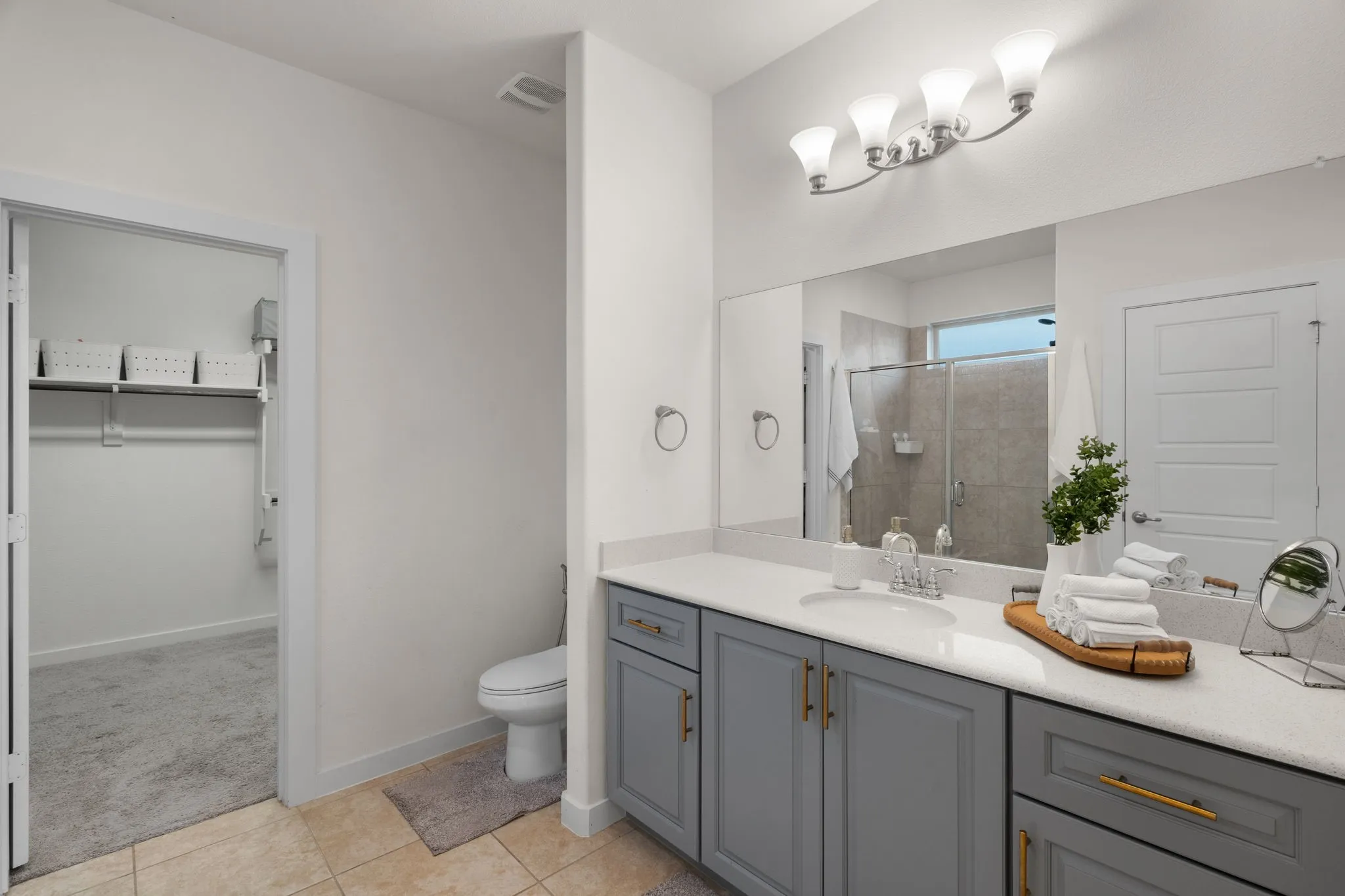 Bathroom featuring a double vanity with gray cabinetry, brushed brass hardware, and a white countertop