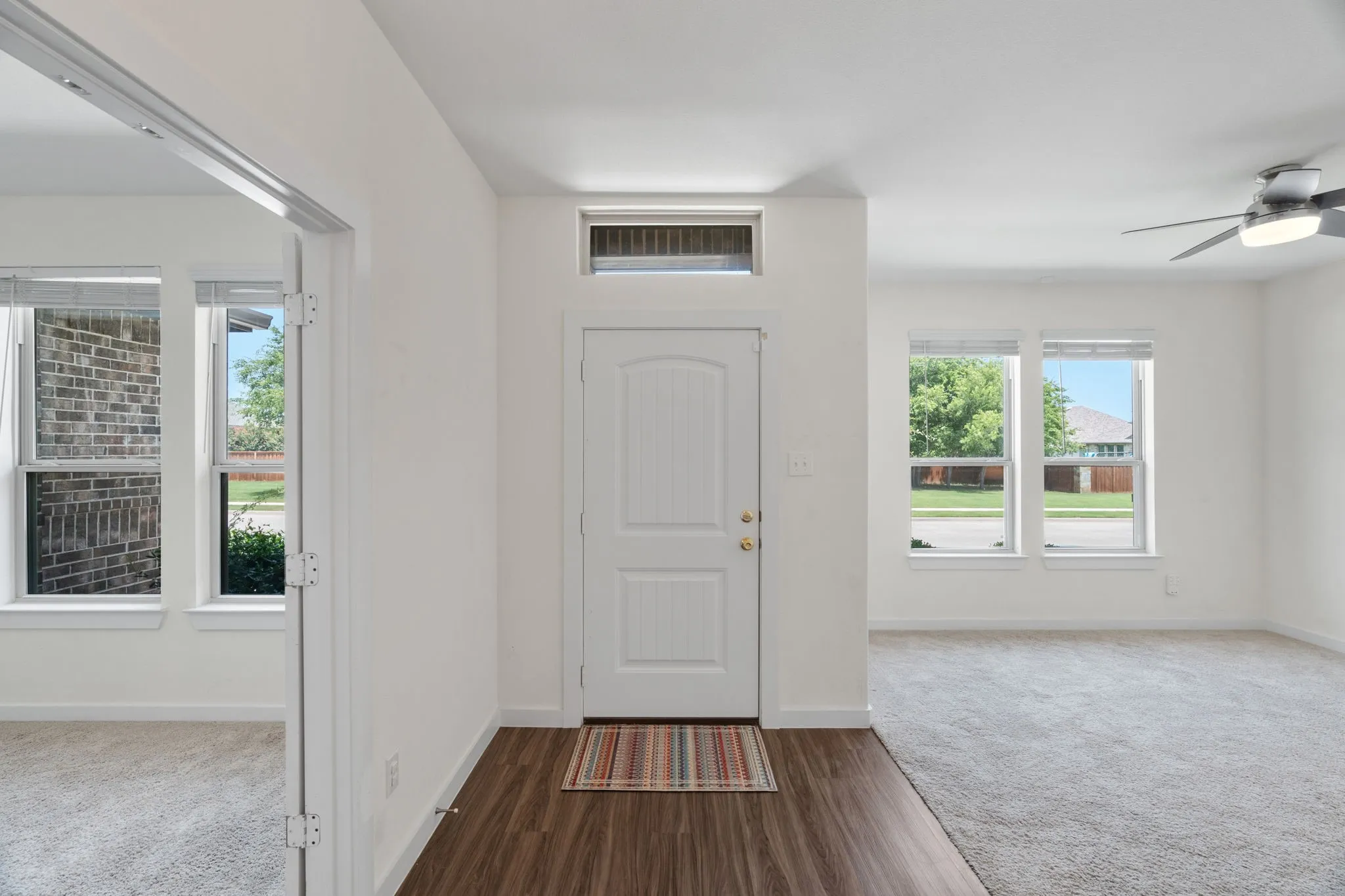 Entryway featuring a paneled door with a transom window, wood-finish flooring, and light-colored walls