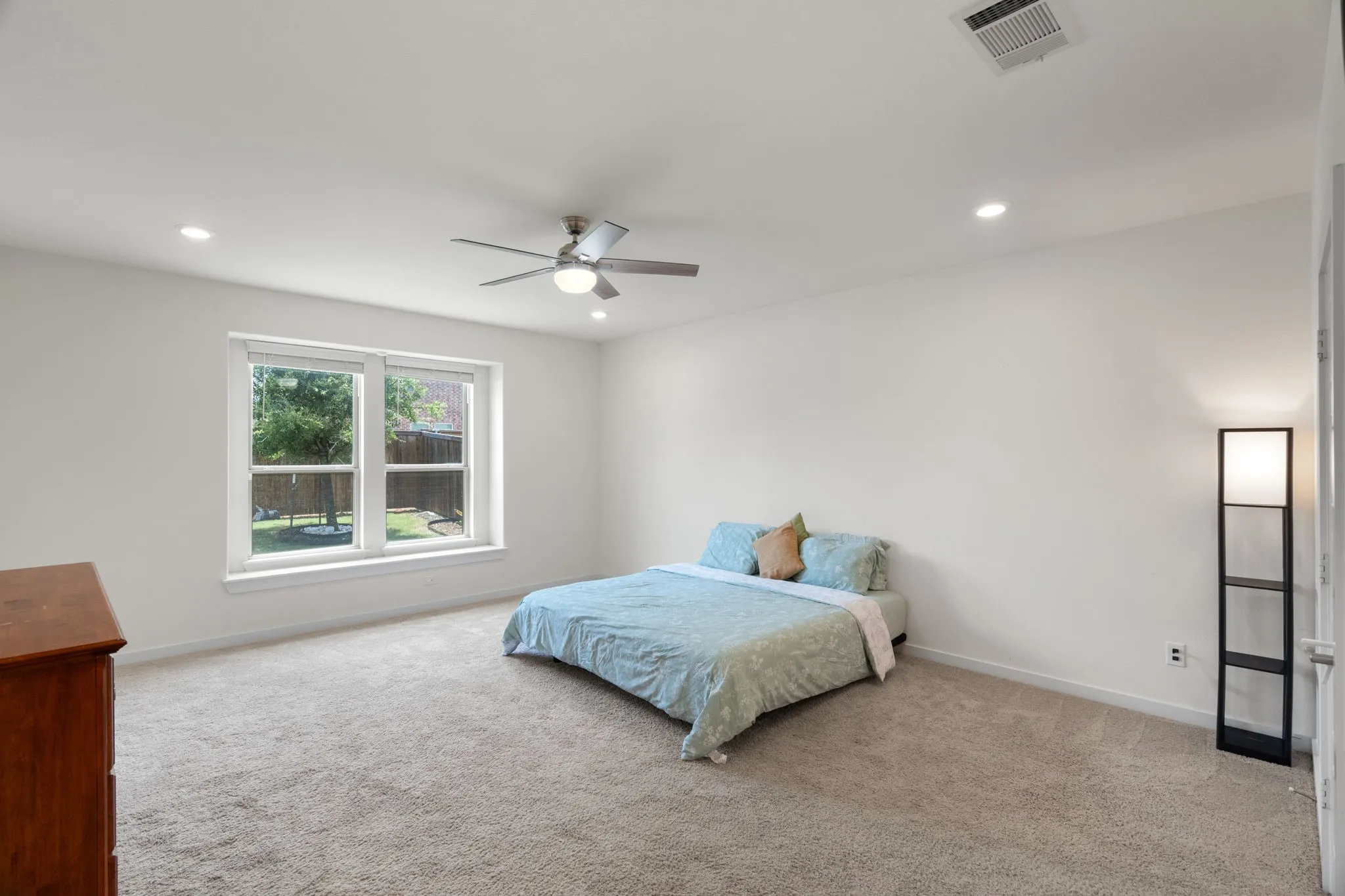 Spacious room featuring neutral carpet, recessed lighting, a ceiling fan, and large windows overlooking the backyard