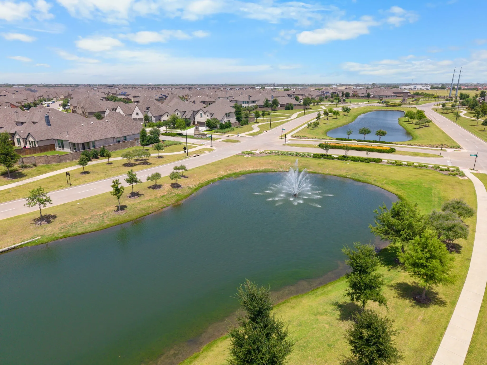 Manicured community landscaping featuring two ponds with a central fountain
