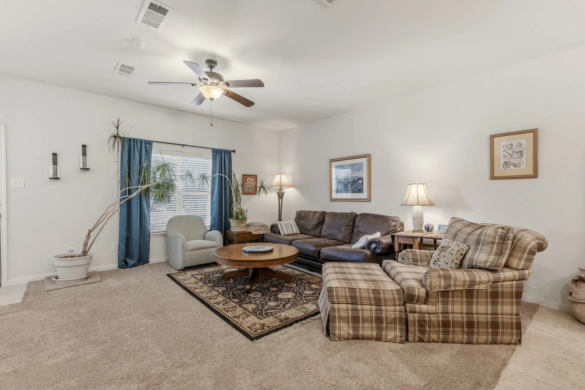Living room featuring light neutral wall paint, carpet flooring, a ceiling fan with integrated lighting, and window with blinds