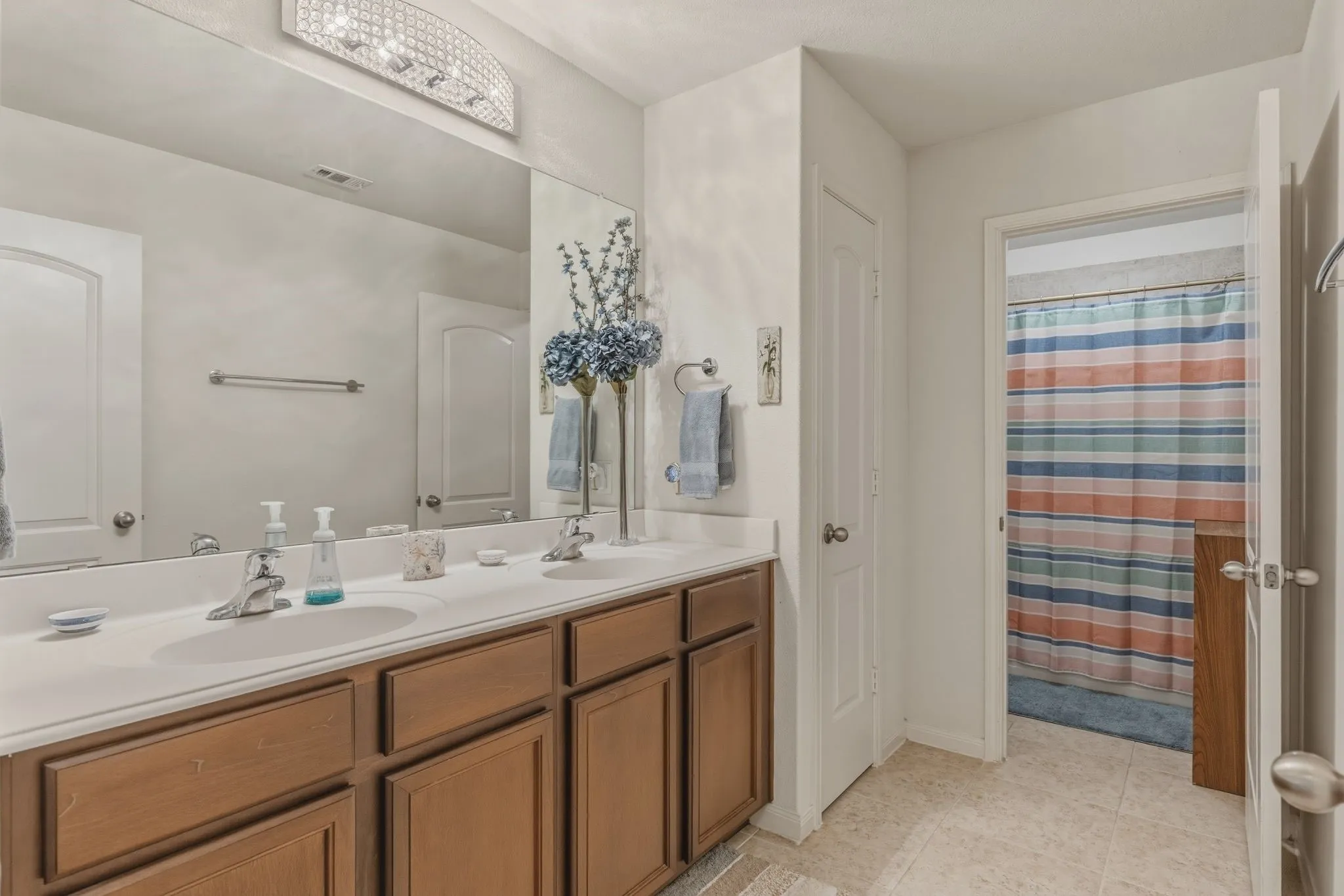 Double vanity featuring two integrated sinks, chrome faucets, and wood-finish cabinetry