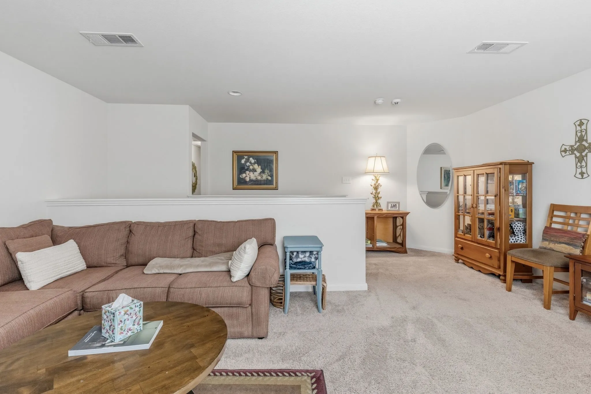 Carpeted family room  featuring a half-wall partition, white walls, and recessed ceiling vents