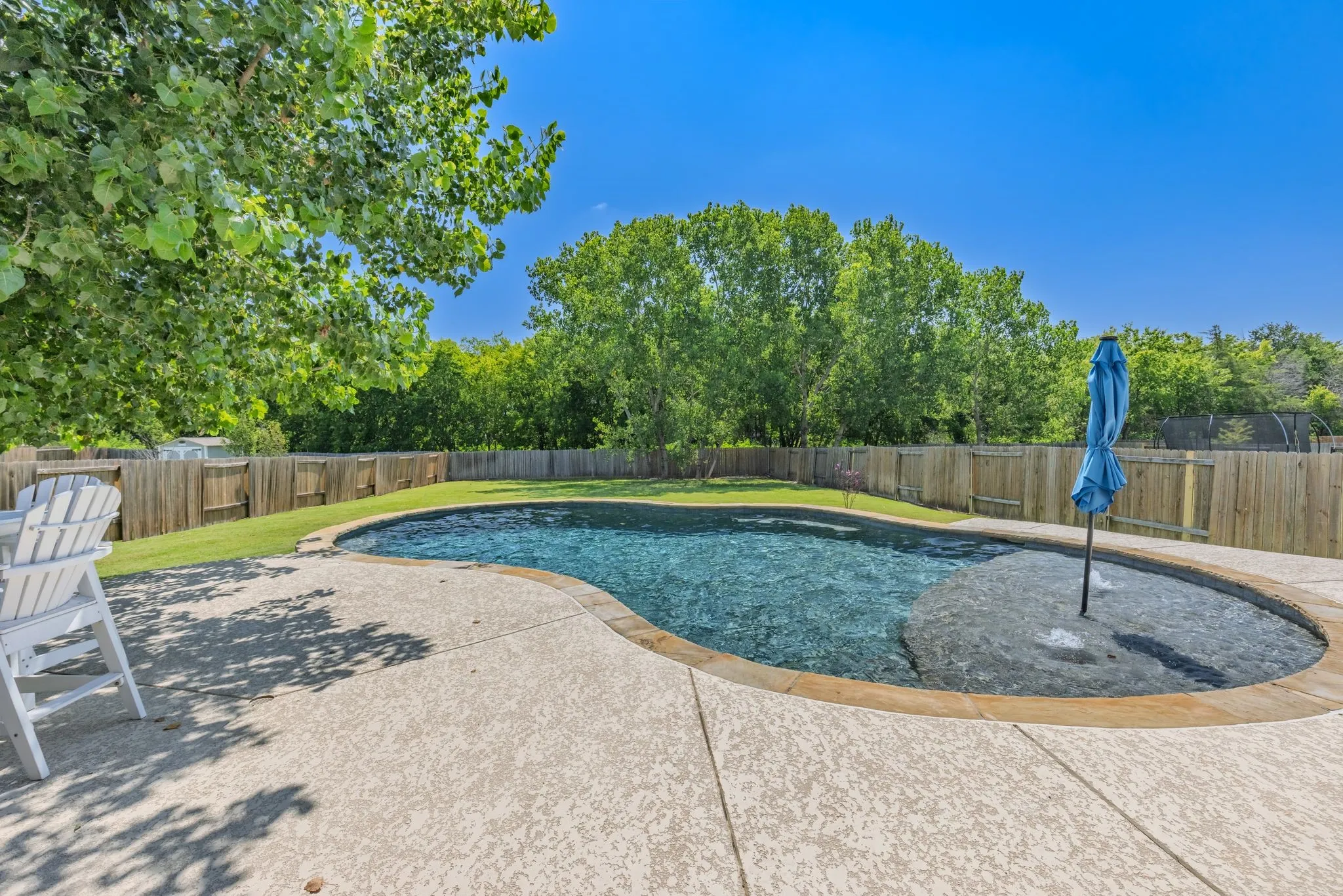 View of pool with sunning deck and view of the large yard.