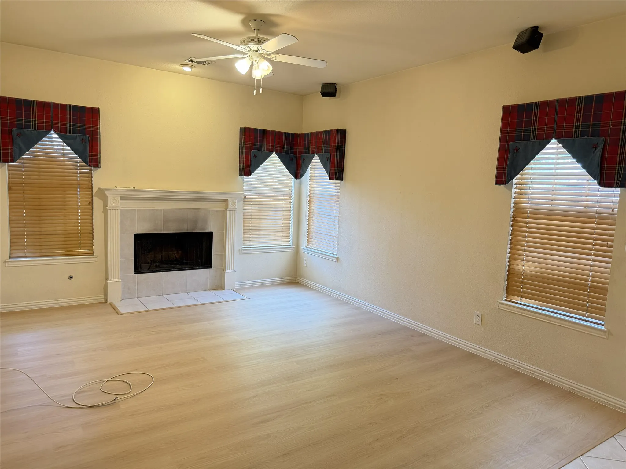 Living area featuring a tiled fireplace with a mantel, wood-finish flooring, and multiple windows with blinds
