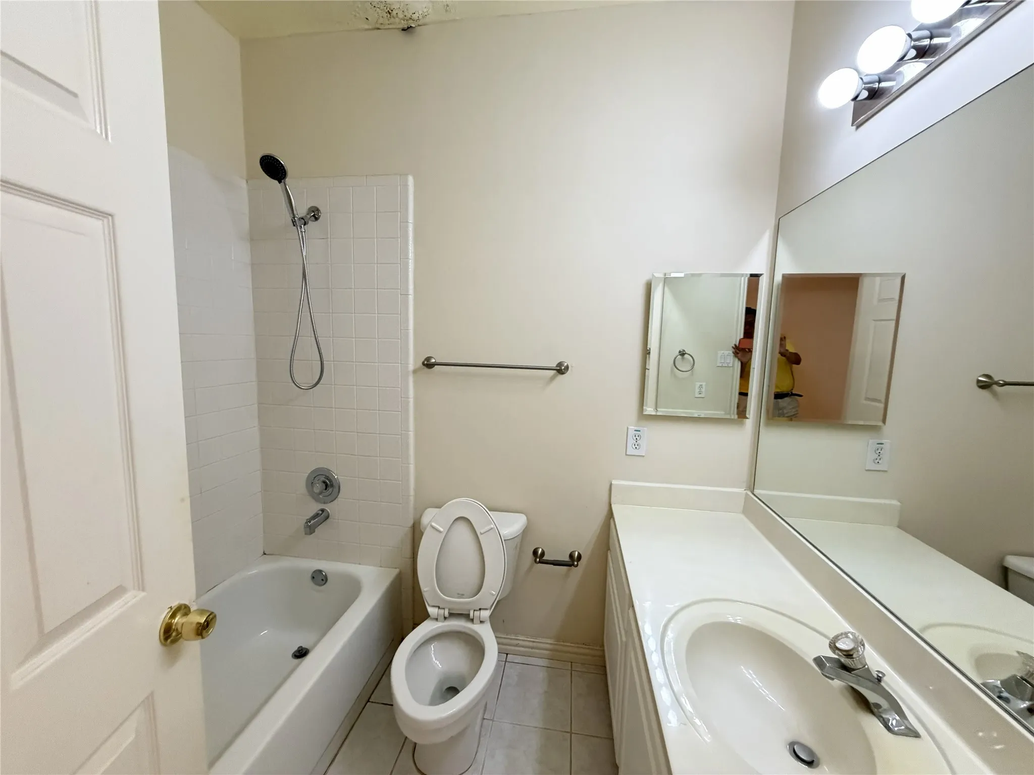 Full bathroom featuring a white tub-shower combination with tiled surround, a white toilet, and a vanity with an integrated sink and countertop