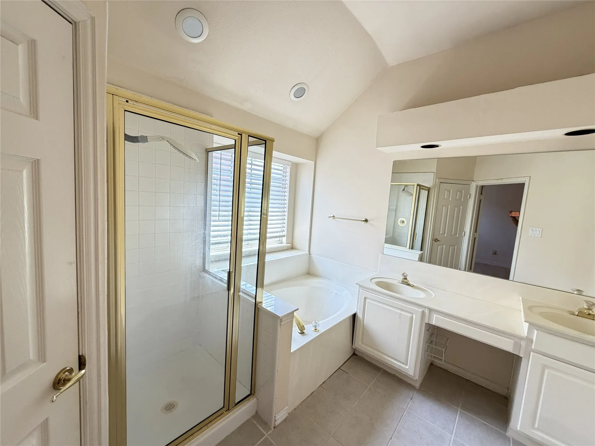 Bathroom featuring a tiled soaking tub and separate shower with a gold-finish frame