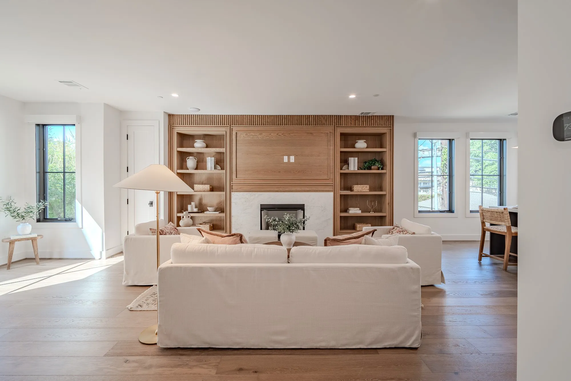 Living room with a high end fireplace, wood-type flooring, and recessed lighting