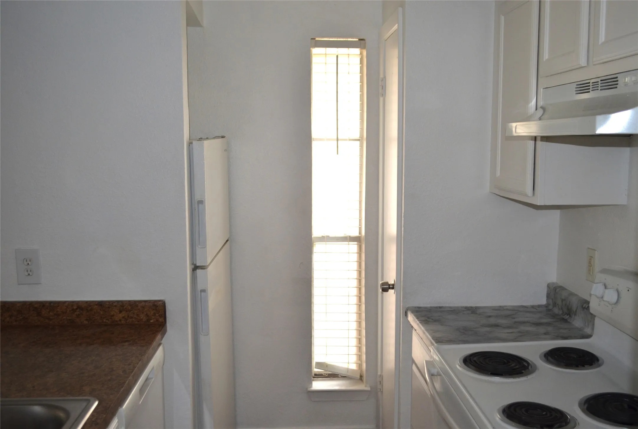 Kitchen featuring white cabinetry, a built-in refrigerator, and a narrow window with blinds