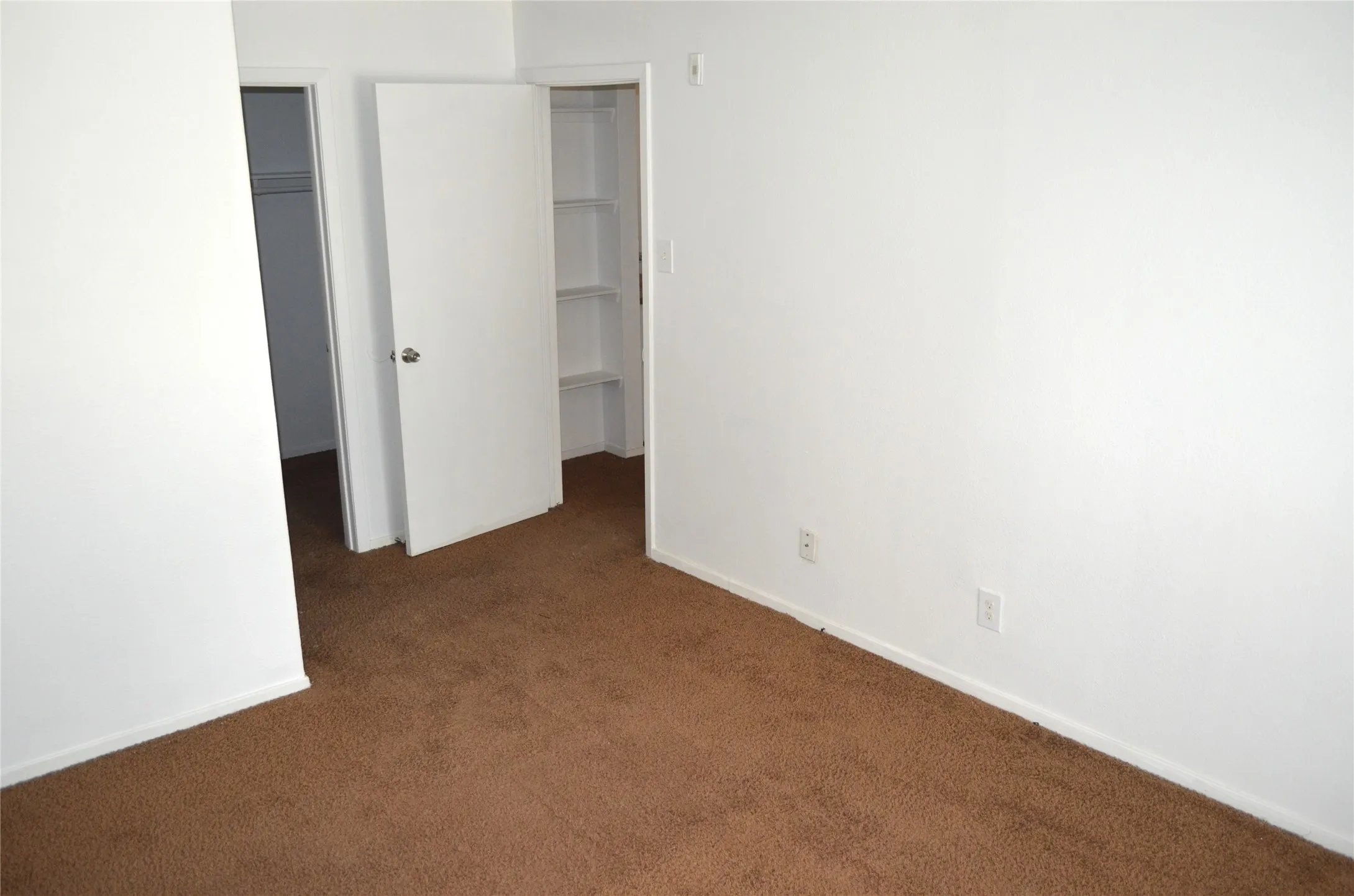 Carpeted room with white walls, baseboards, and two doorways
