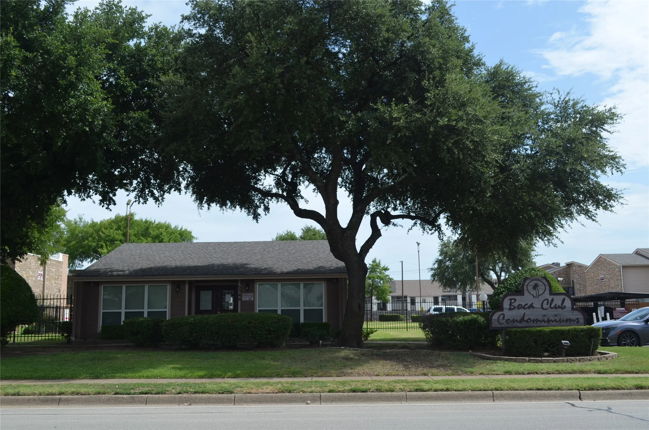 Low-rise condominium building featuring a dark shingle roof and a central entrance