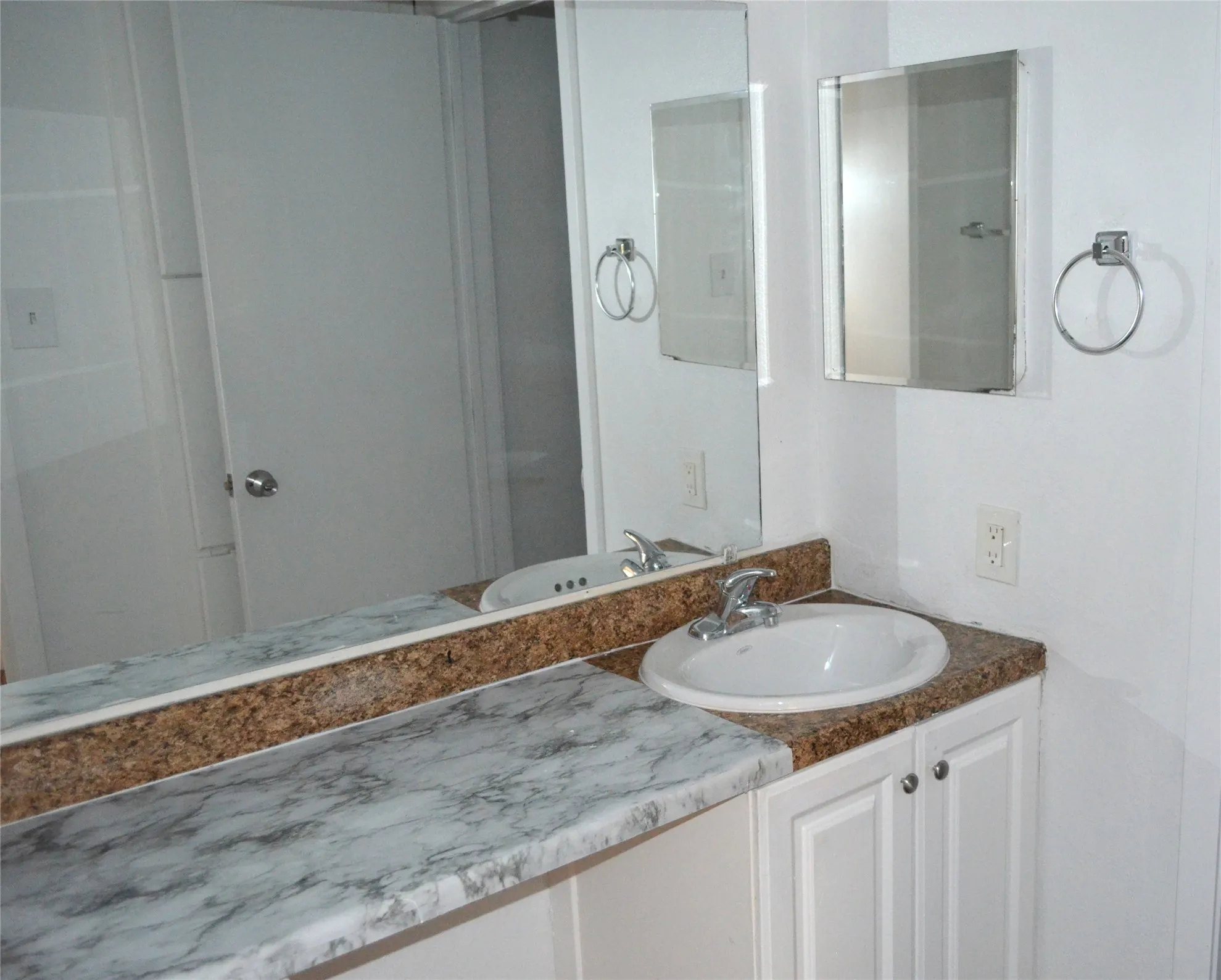 Vanity area featuring a drop-in sink, white cabinetry with silver hardware, and a countertop with both a stone-look and speckled finish