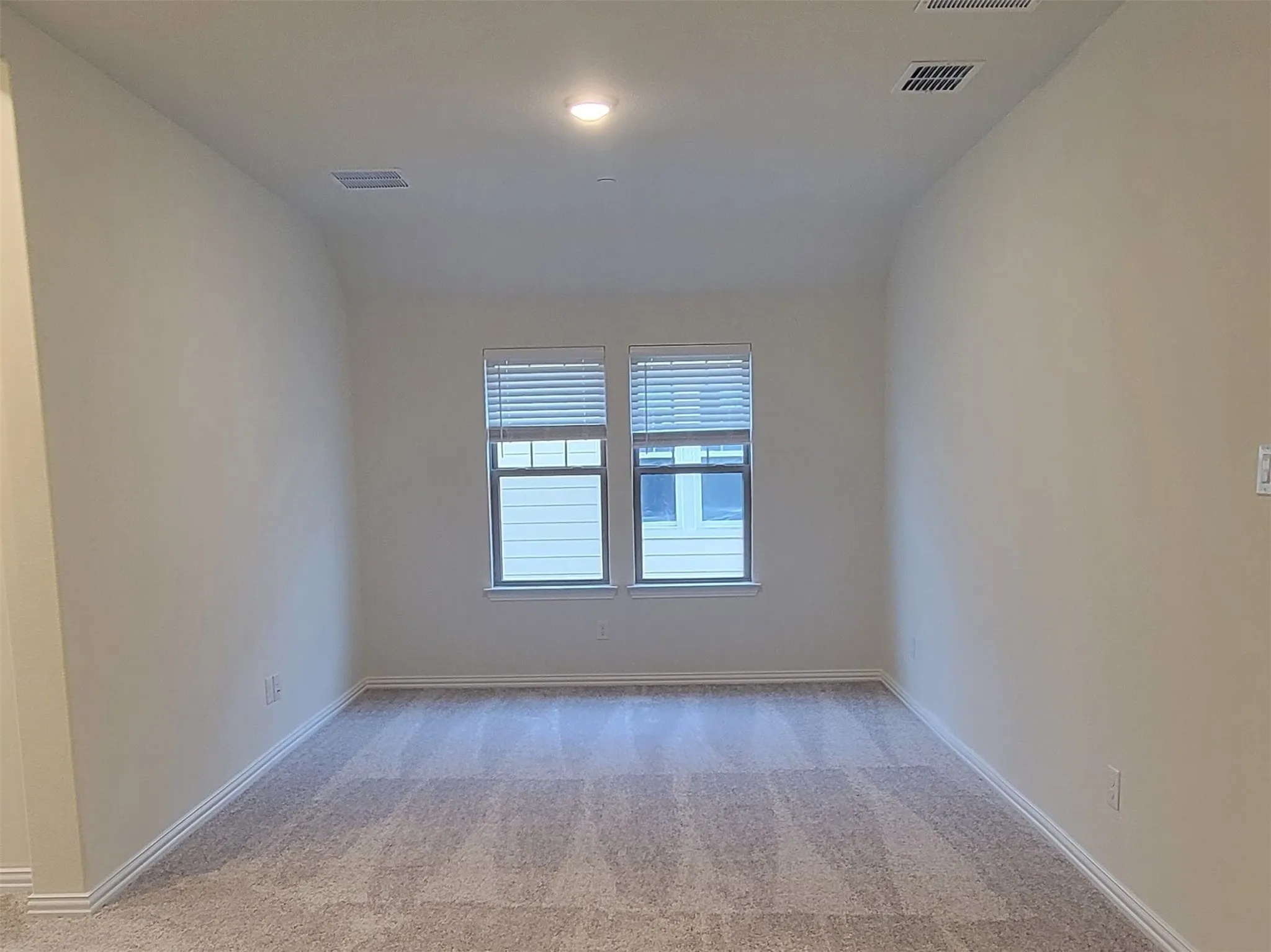 Carpeted room featuring two windows with blinds, recessed lighting, and white baseboards