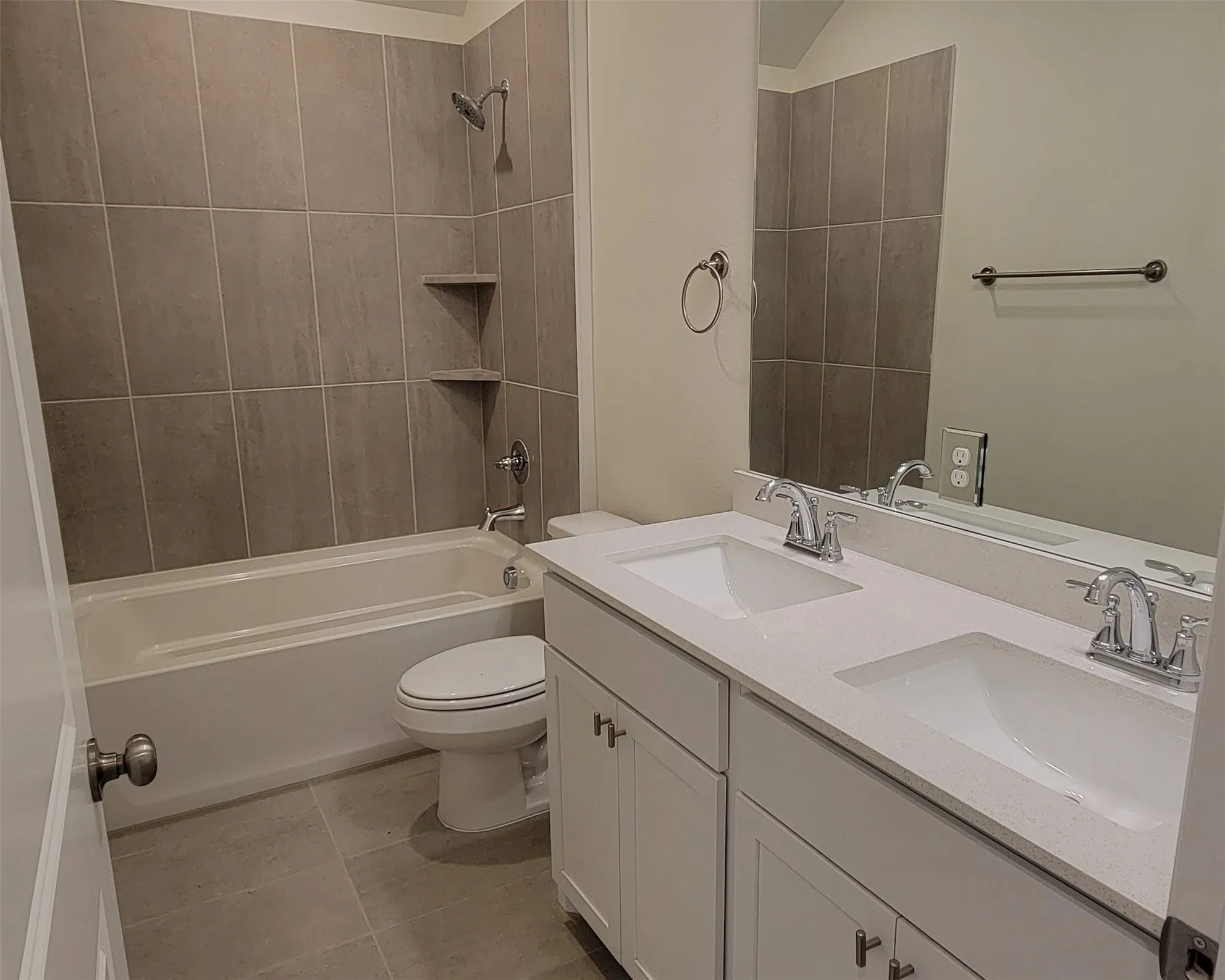Bathroom with dual vanity featuring built-in sinks, a solid surface countertop, and white shaker-style cabinetry