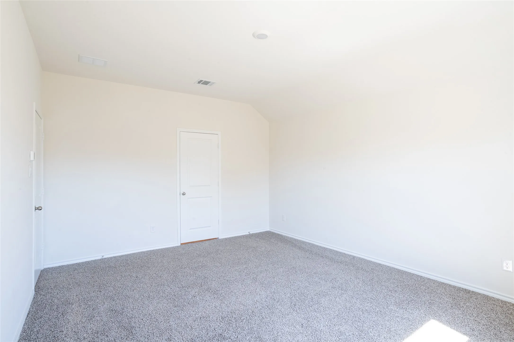 Carpeted master bedroom featuring lofted ceiling, bedroom door (left), and master bathroom door (right)
