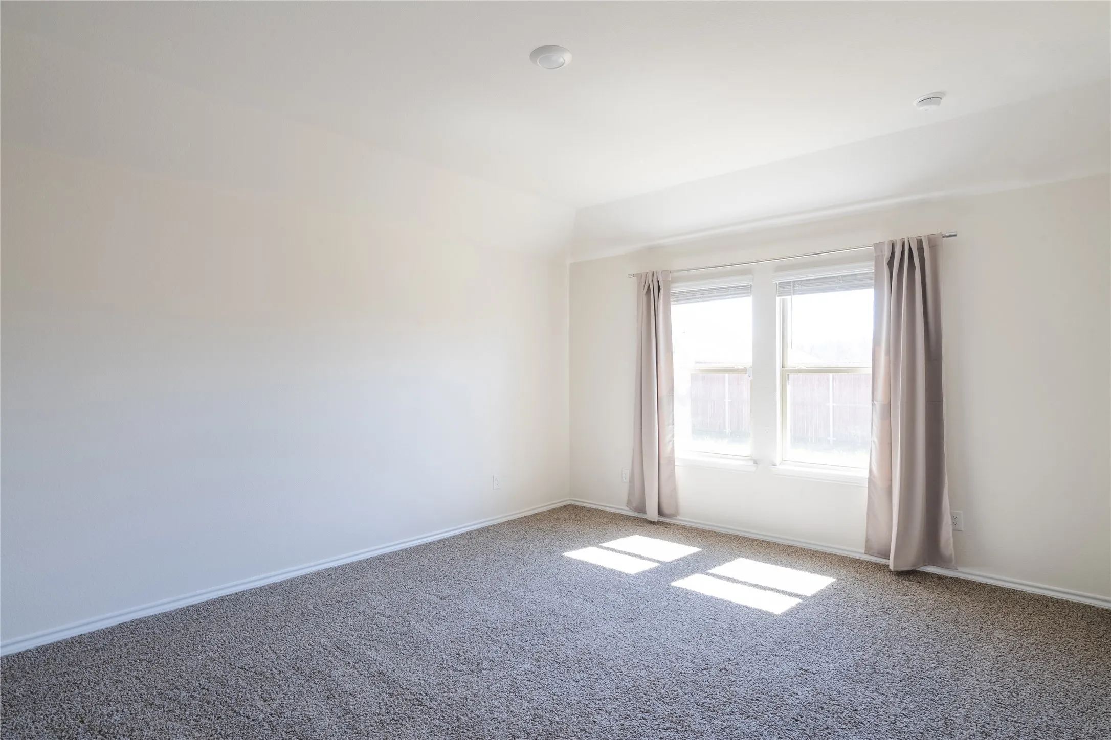 Carpeted master bedroom featuring lofted ceiling and backyard view