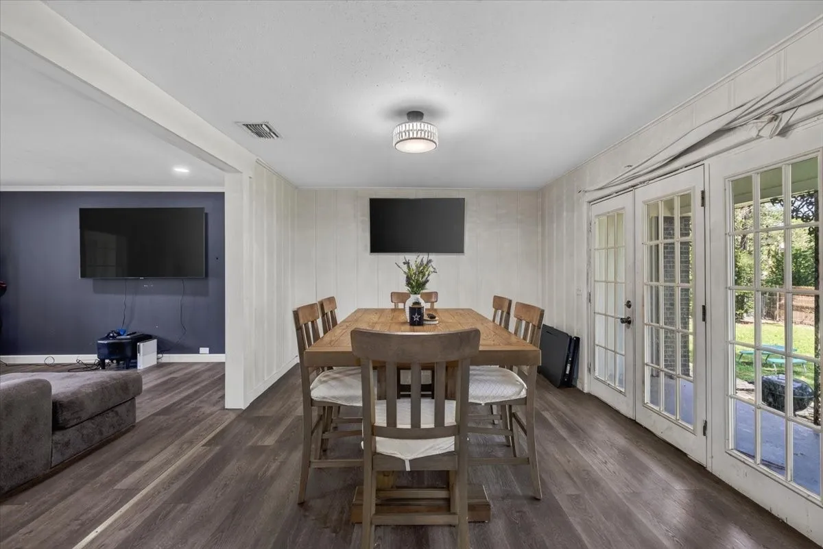 Dining area featuring wood-finish flooring, white vertical wall paneling, and a modern flush-mount light fixture
