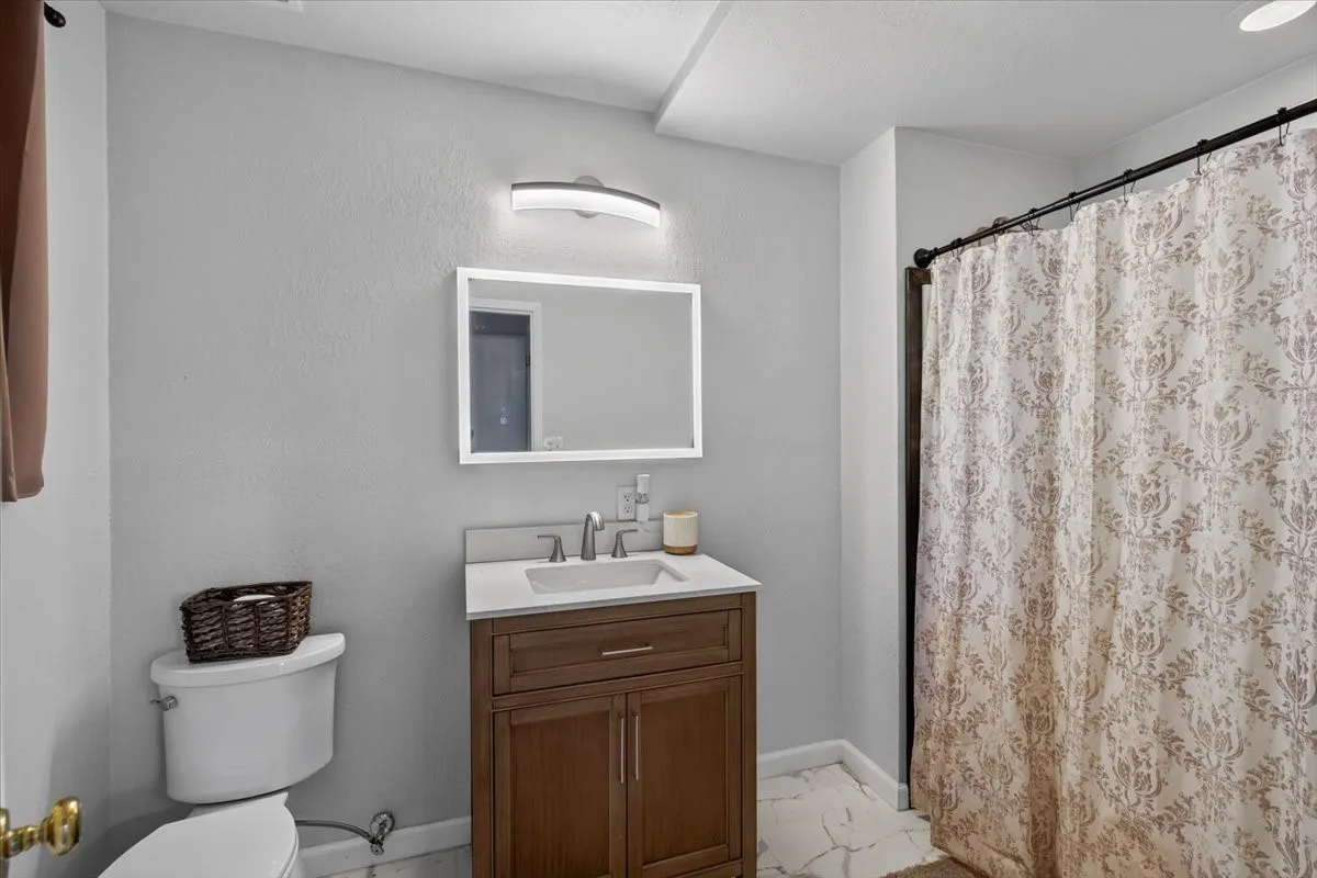 Bathroom featuring a wood-finish vanity with a white countertop and rectangular sink