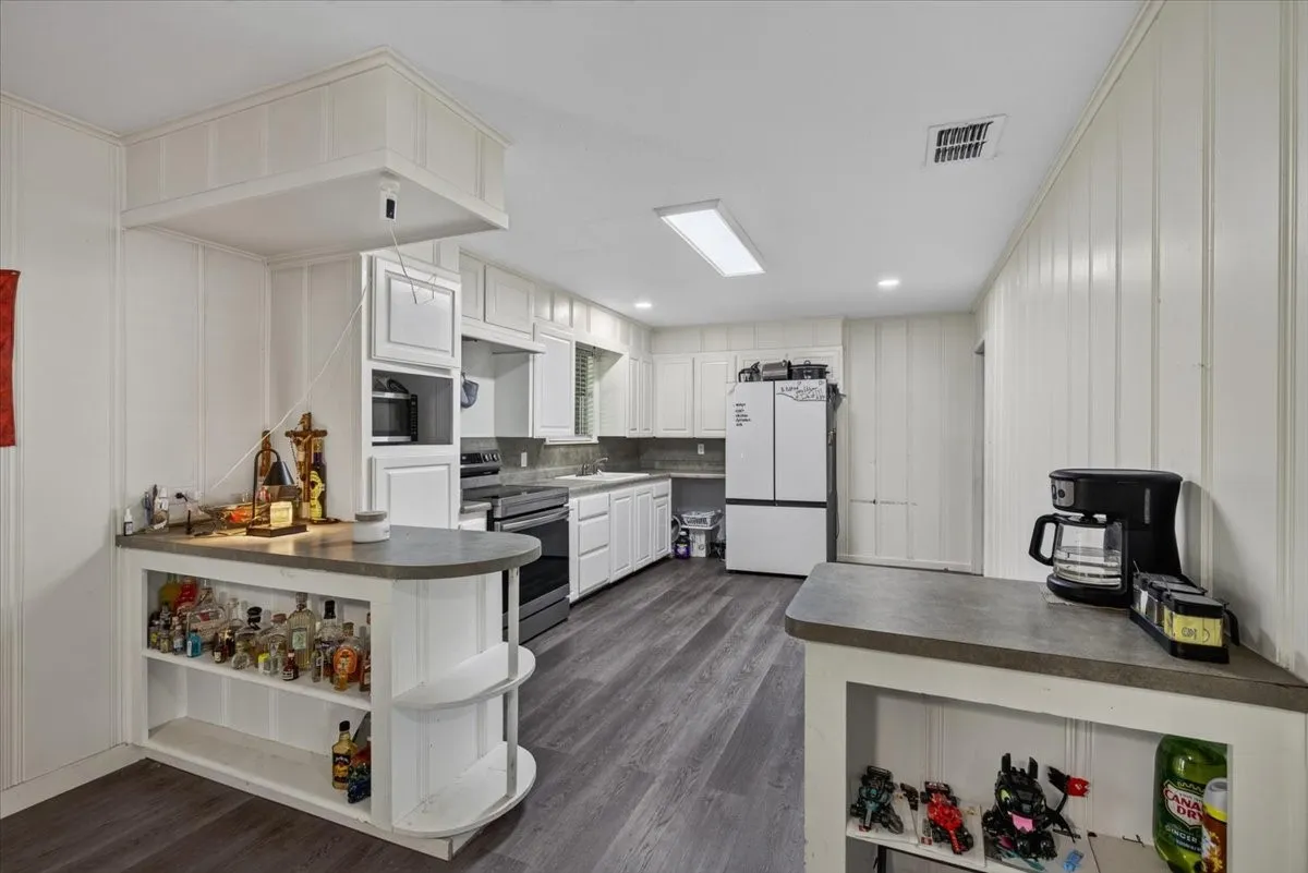 Kitchen featuring white cabinetry, grey countertops, stainless steel appliances, and wood-finish flooring