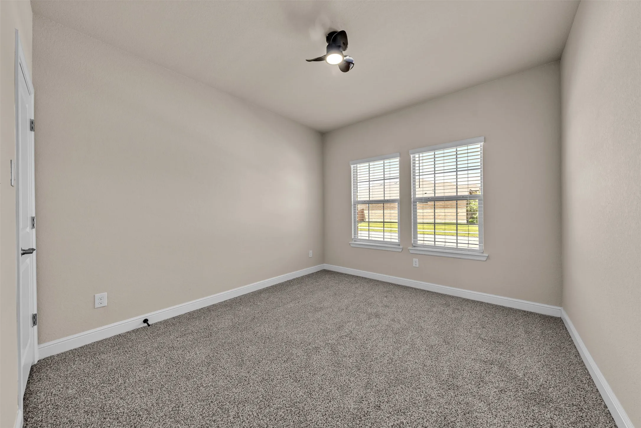 Vaulted ceiling room featuring light neutral walls and gray carpet flooring
