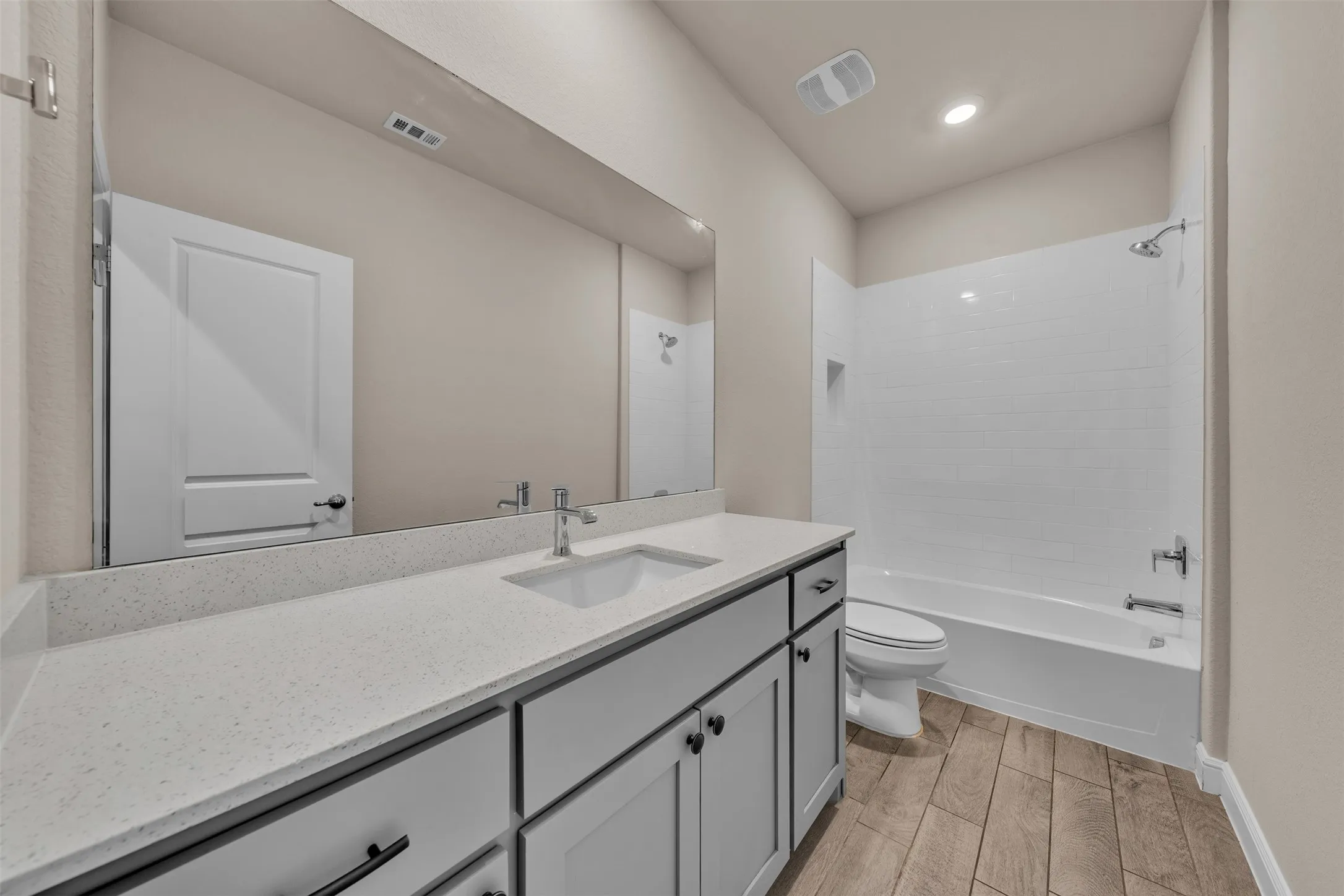 Bathroom featuring a wide vanity with a light-toned countertop, an integrated sink, and dark cabinetry