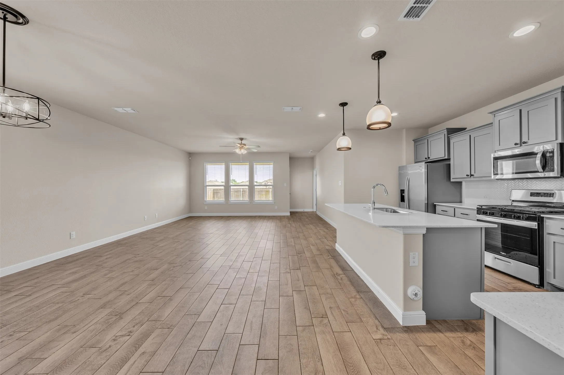 Spacious open-concept living area featuring wood-finish flooring, recessed lighting, and a ceiling fan