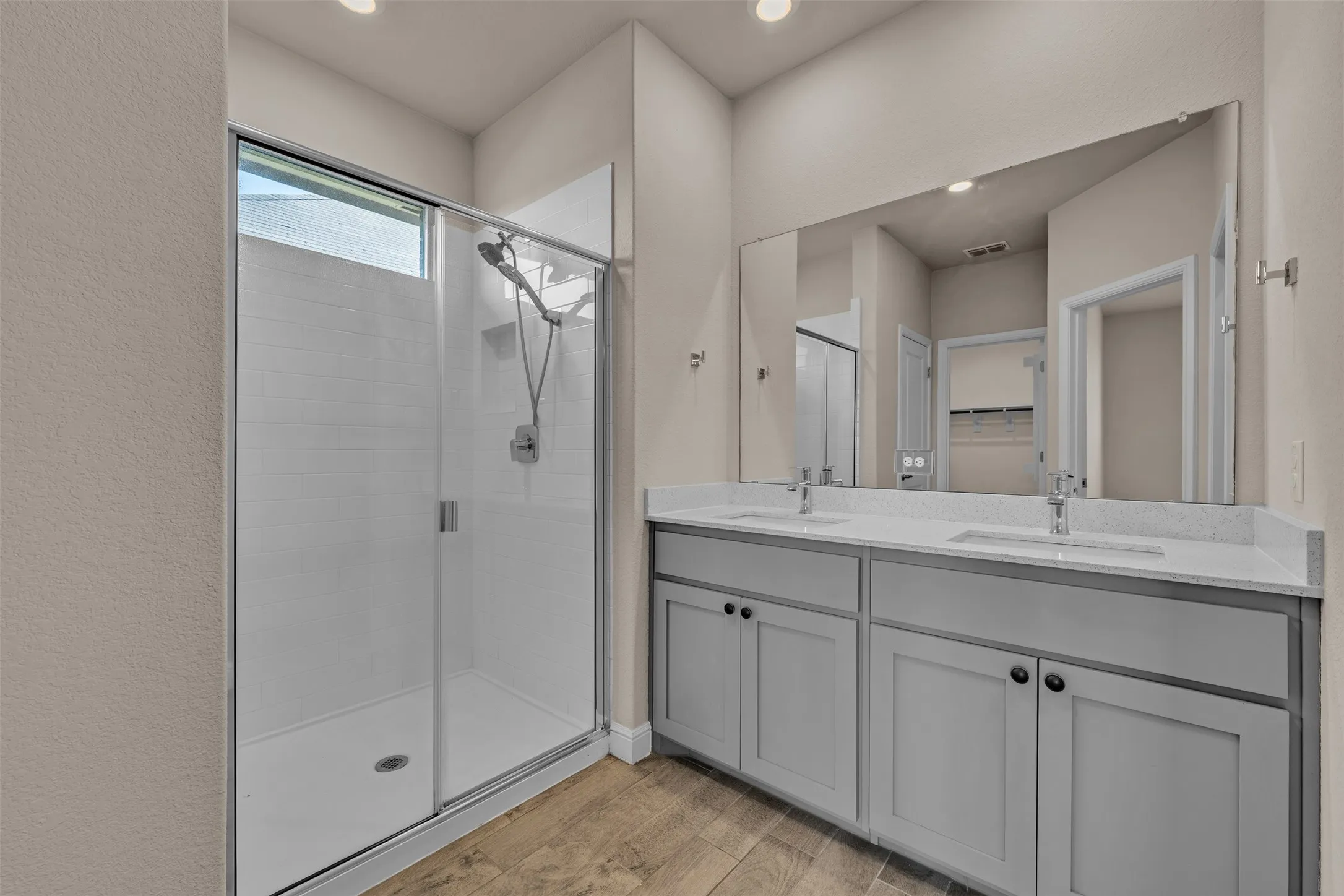 Modern bathroom featuring a double vanity with grey cabinetry, white countertops, and dual undermount sinks