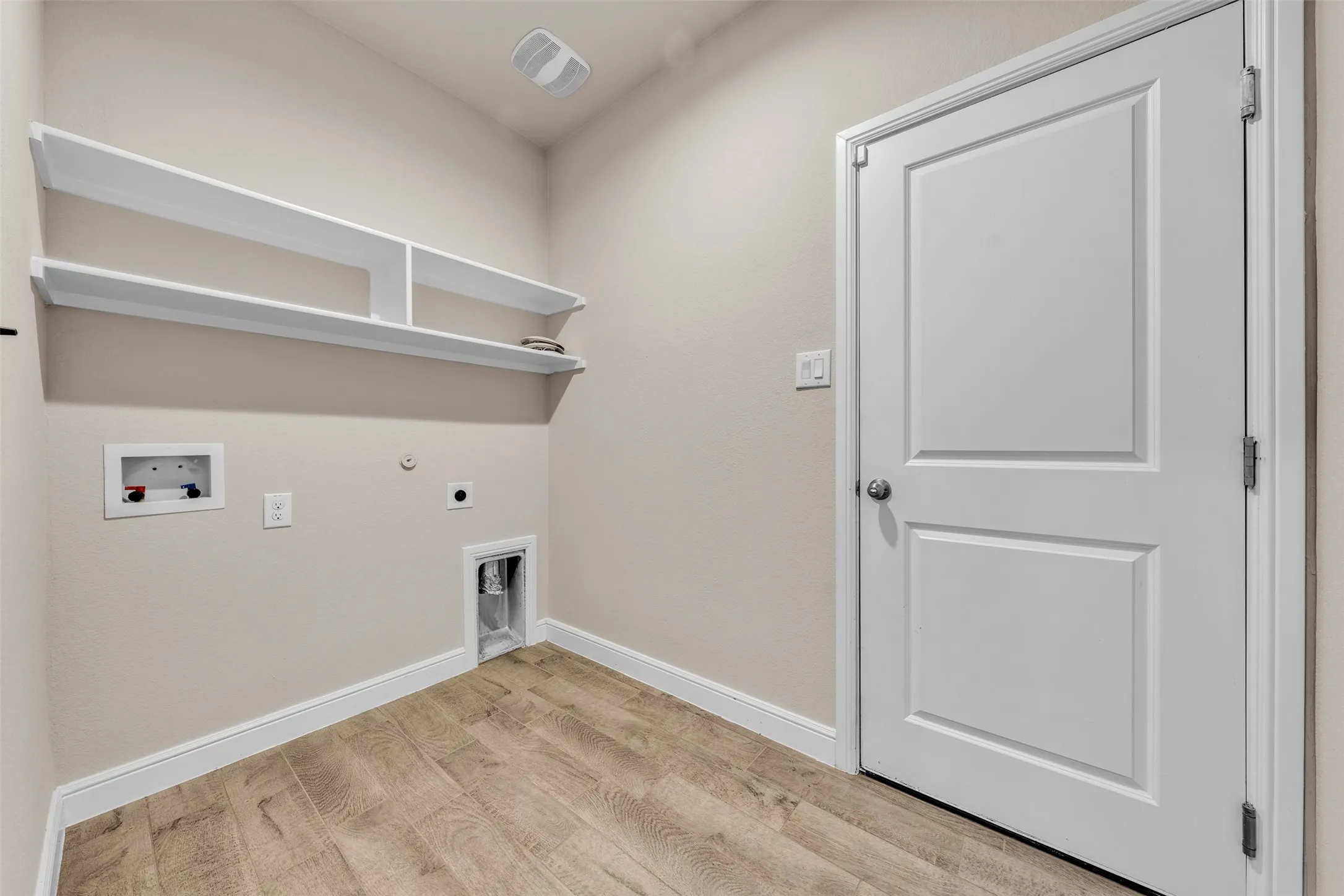 Utility space featuring wood-finish flooring, light neutral wall color, and white trim