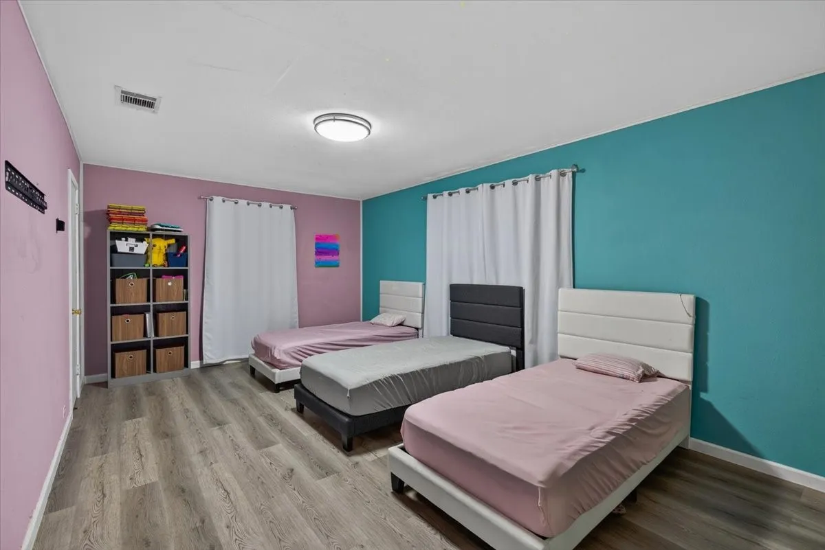 Spacious room featuring wood-finish flooring and a contemporary ceiling light fixture