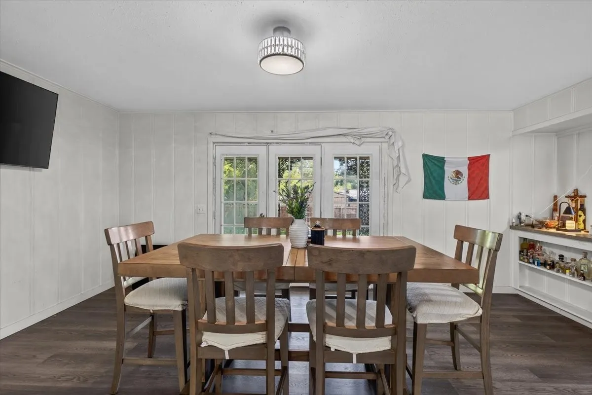 Dining area with wood-finish flooring, white paneling, and a contemporary ceiling light fixture