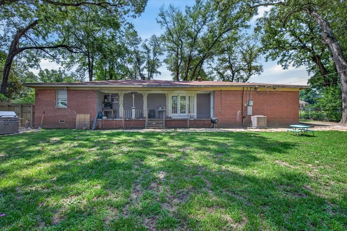 Spacious rear yard with mature trees providing overhead canopy