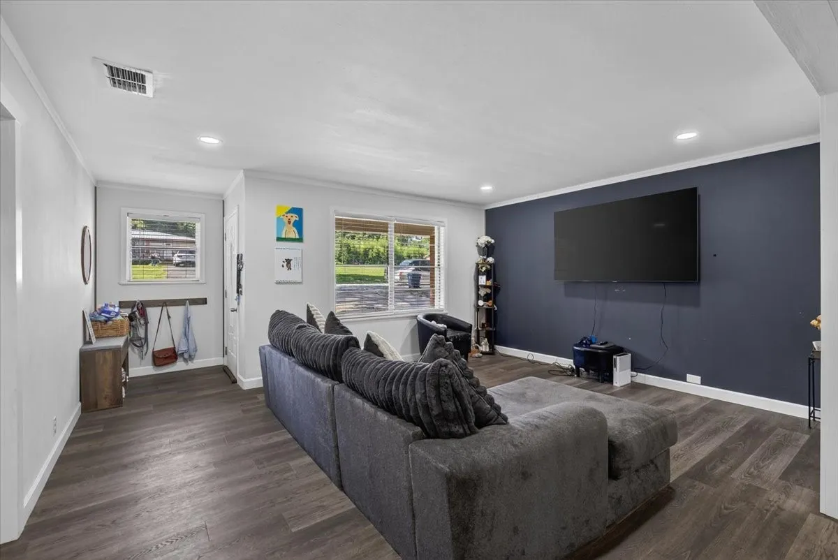 Spacious room featuring wood-finish flooring, recessed lighting, and a prominent accent wall