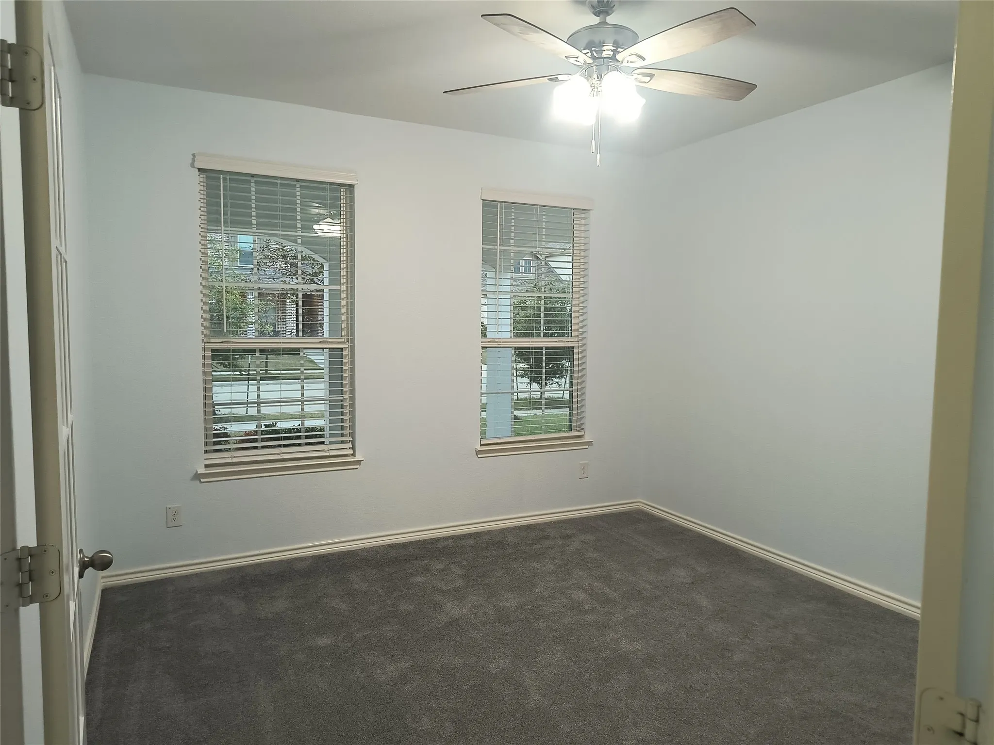 Room featuring two windows with horizontal blinds, neutral wall paint, and gray carpet flooring