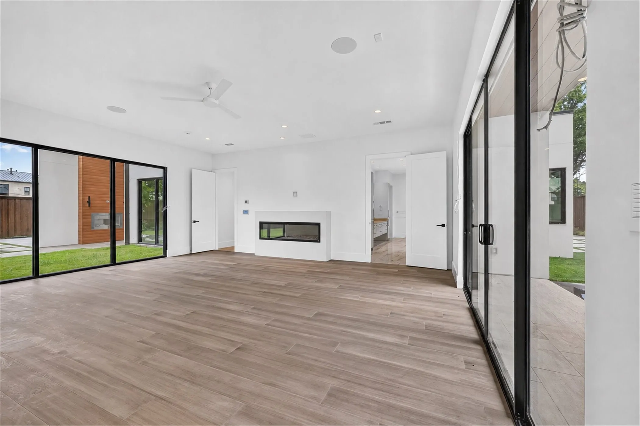 Wood-finish flooring throughout, featuring a linear fireplace, recessed lighting, and a ceiling fan