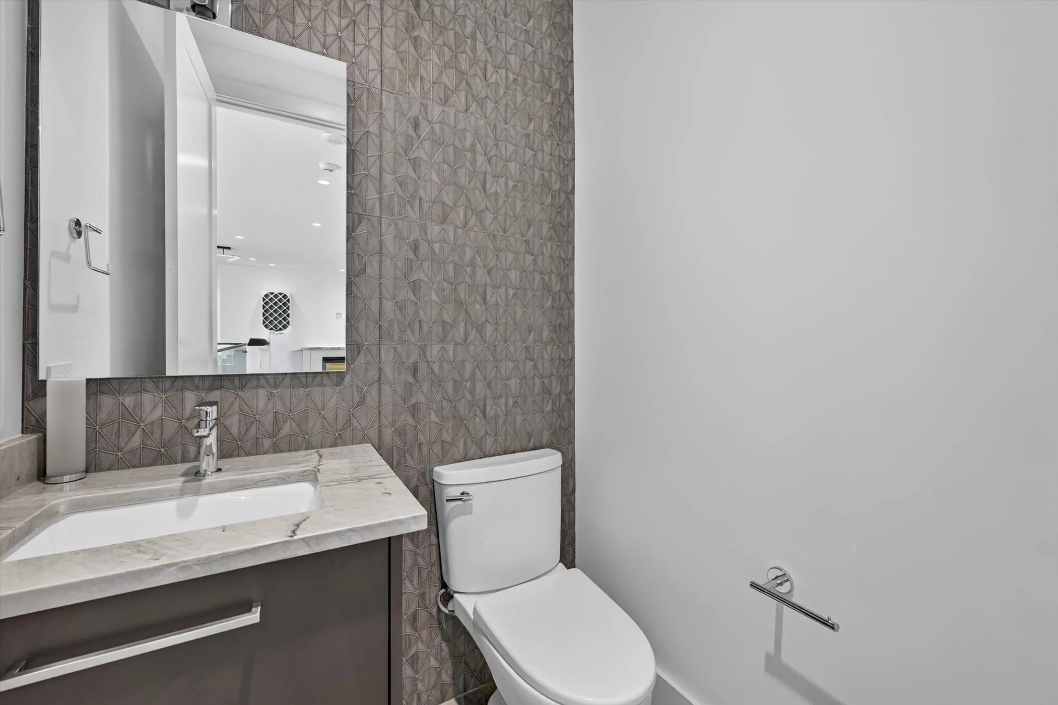 Powder room featuring a modern vanity with integrated sink, stone-finish countertop, and a contemporary wall-mounted mirror