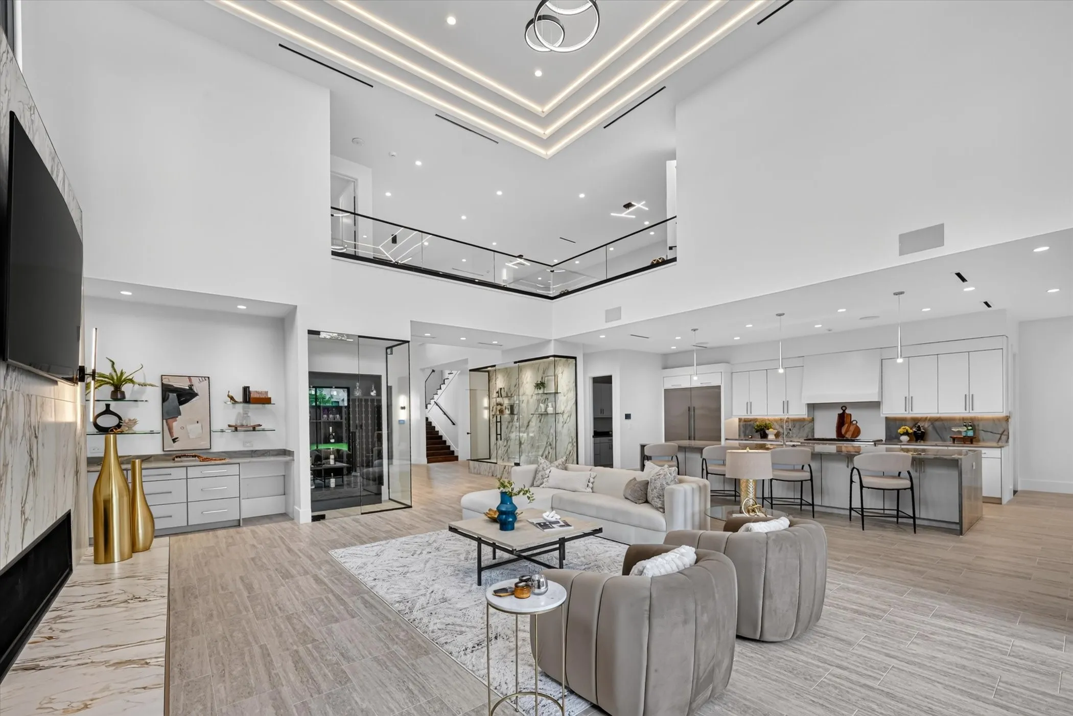 Two-story living area with high ceilings, linear ceiling lighting, and wood-finish flooring