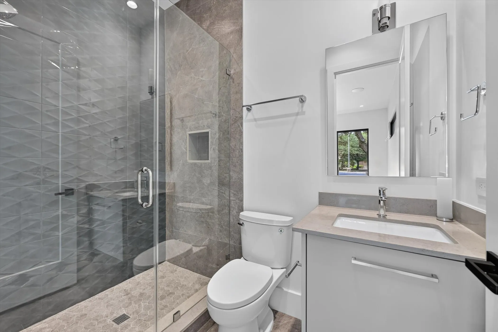 Glass-enclosed shower with a textured tile surround and stone flooring