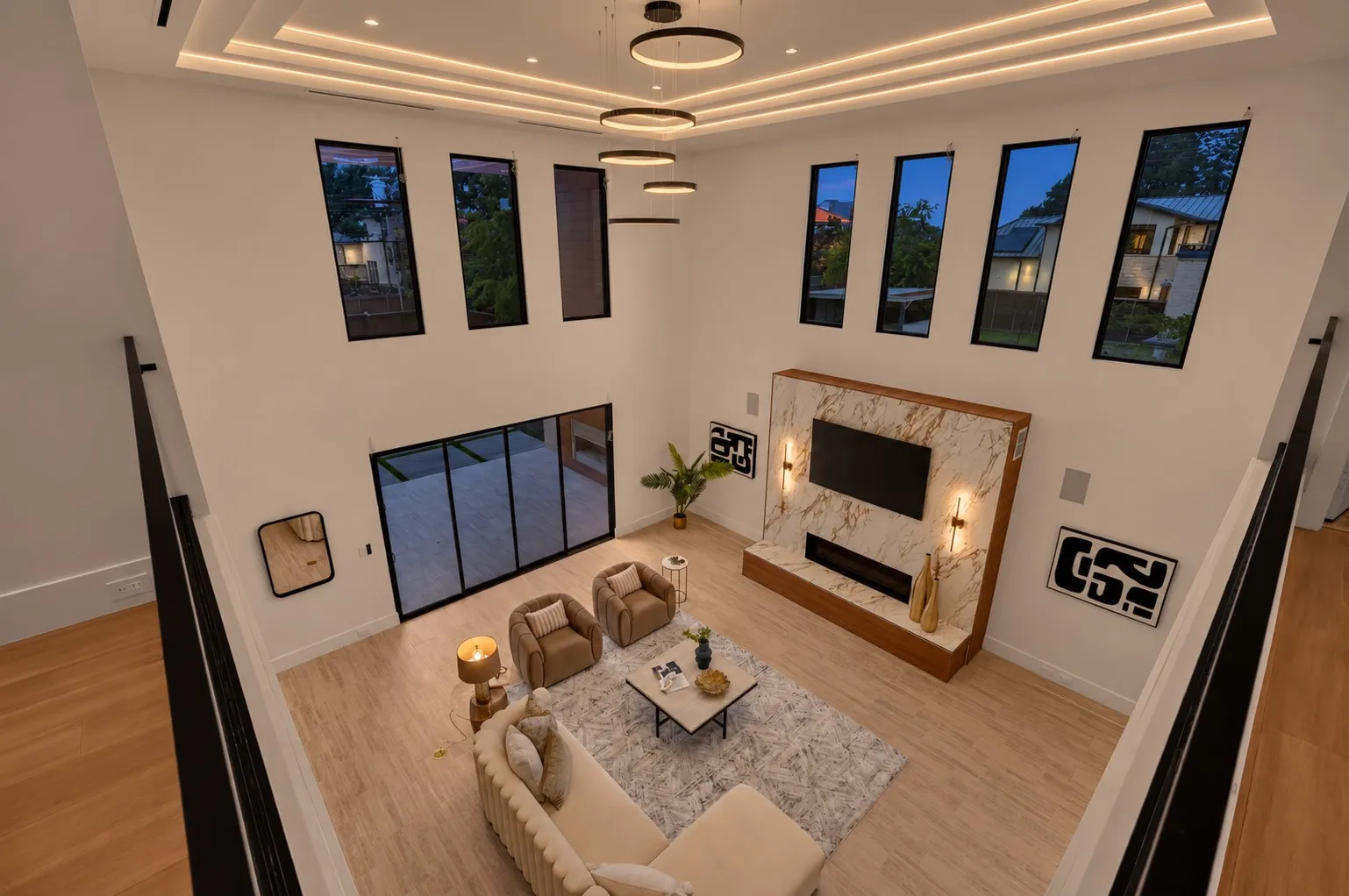 Two-story living area with high ceilings, recessed lighting, and a large fireplace featuring a stone surround and wood hearth