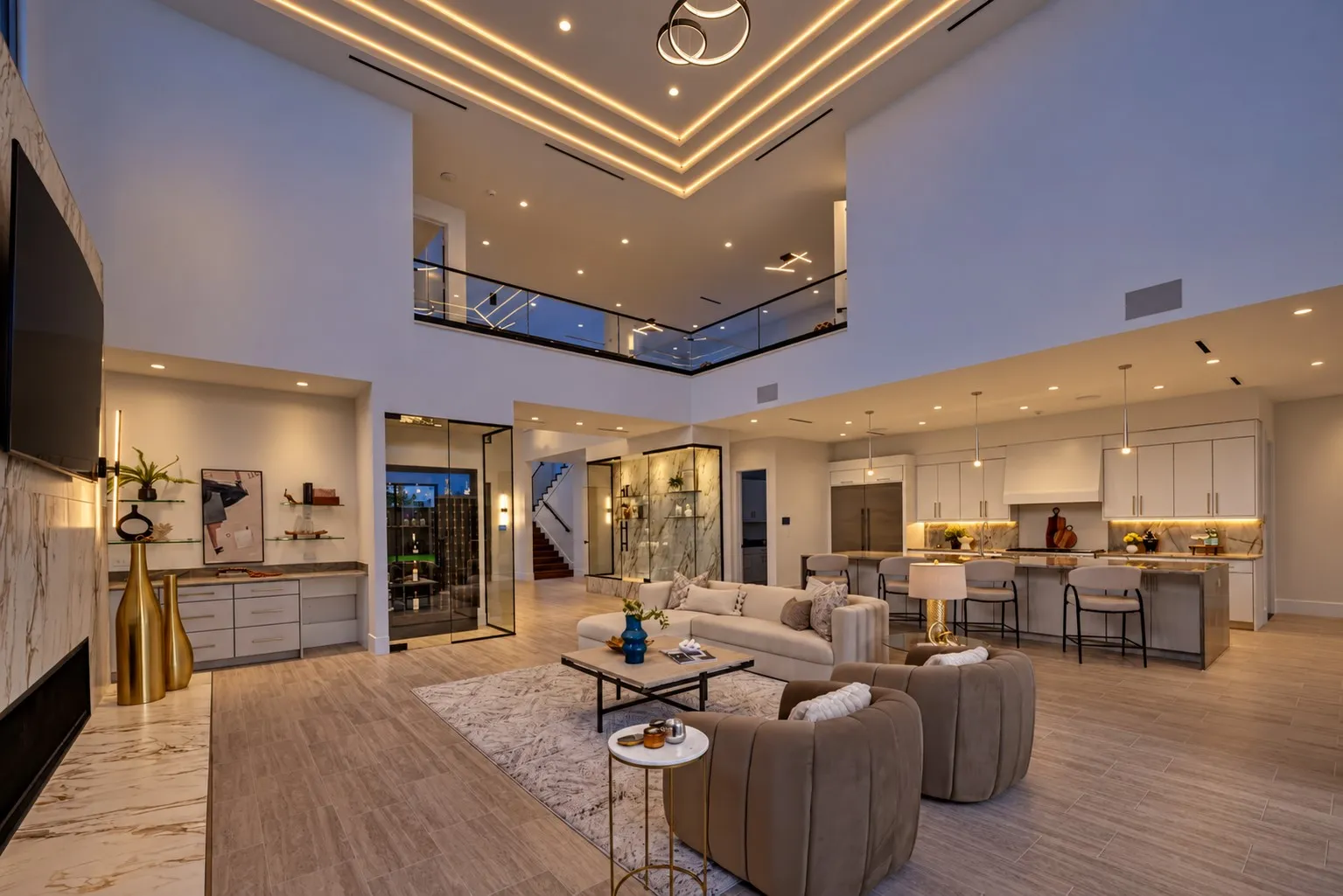 Two-story open-concept living area with a gourmet kitchen, full-height decorative wall paneling, and wood-finish flooring